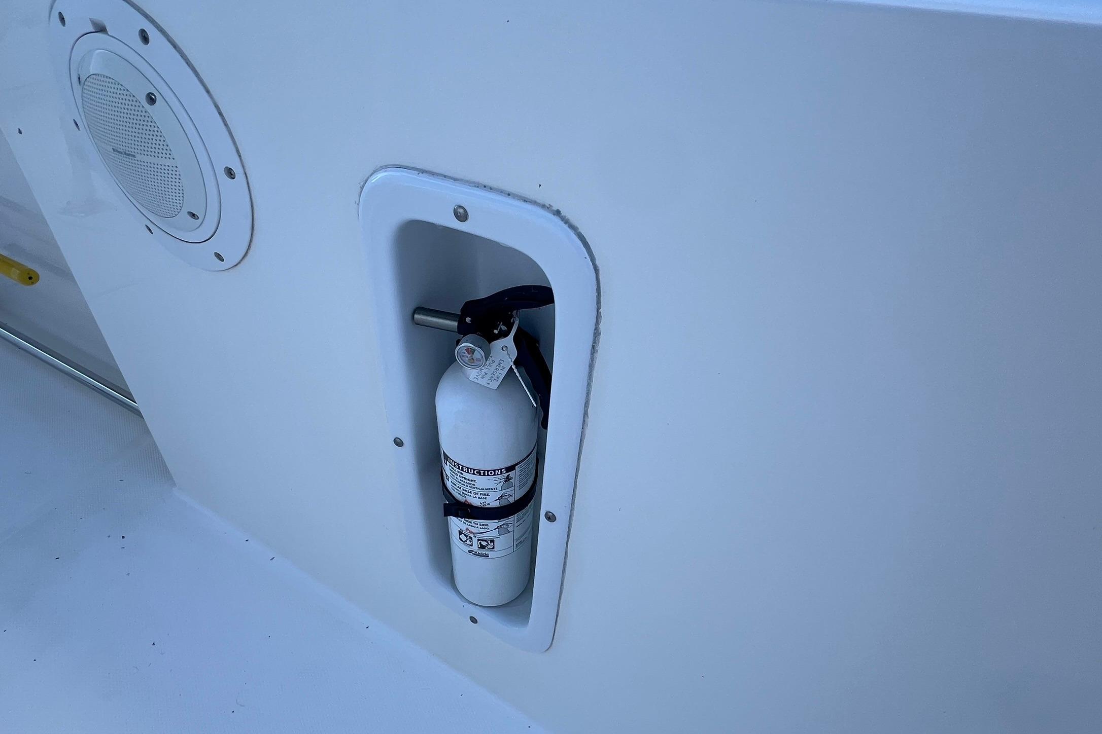 Fire extinguisher mounted on 2006 Edgewater 245CC boat, near speaker.
