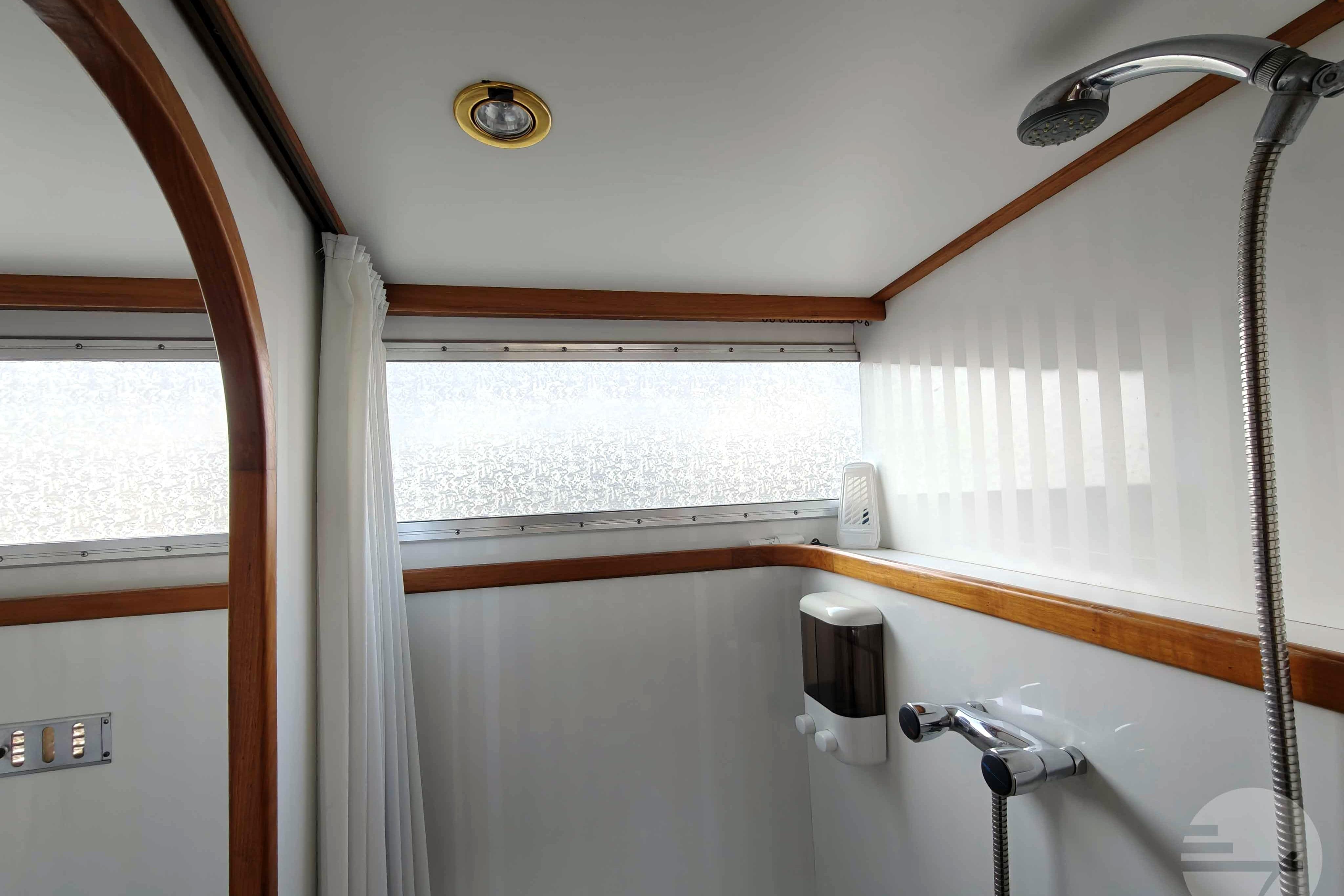 Bathroom interior of 1997 Proficiat 12.25 GL boat with shower and wooden trim.