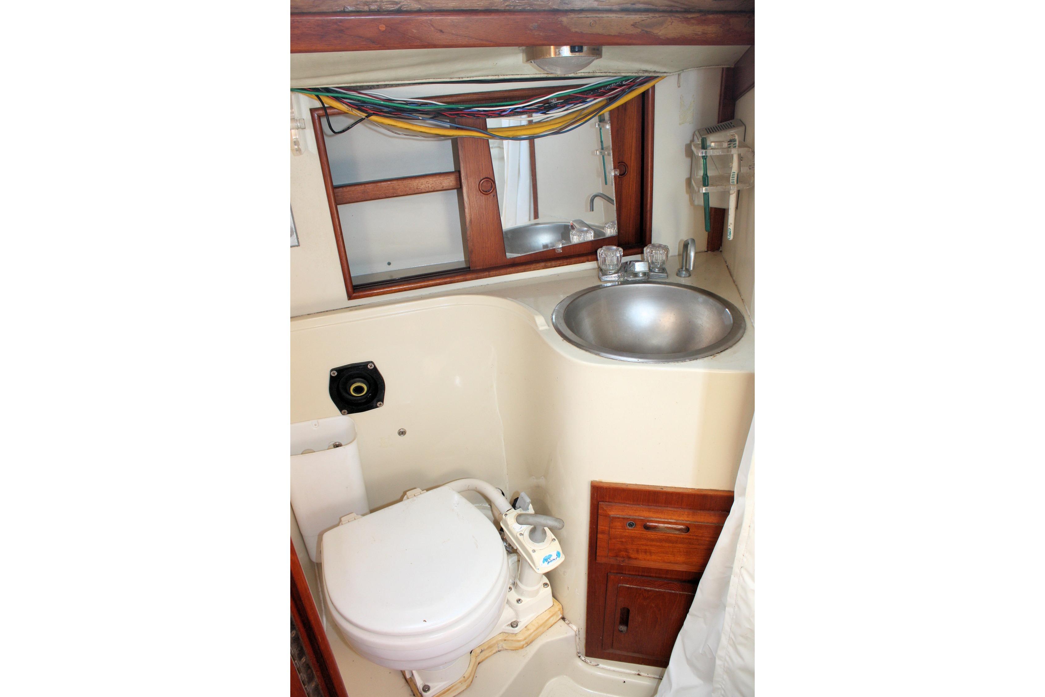 Compact bathroom in 1987 Ericson 38-200 sailboat with sink, toilet, and mirror.