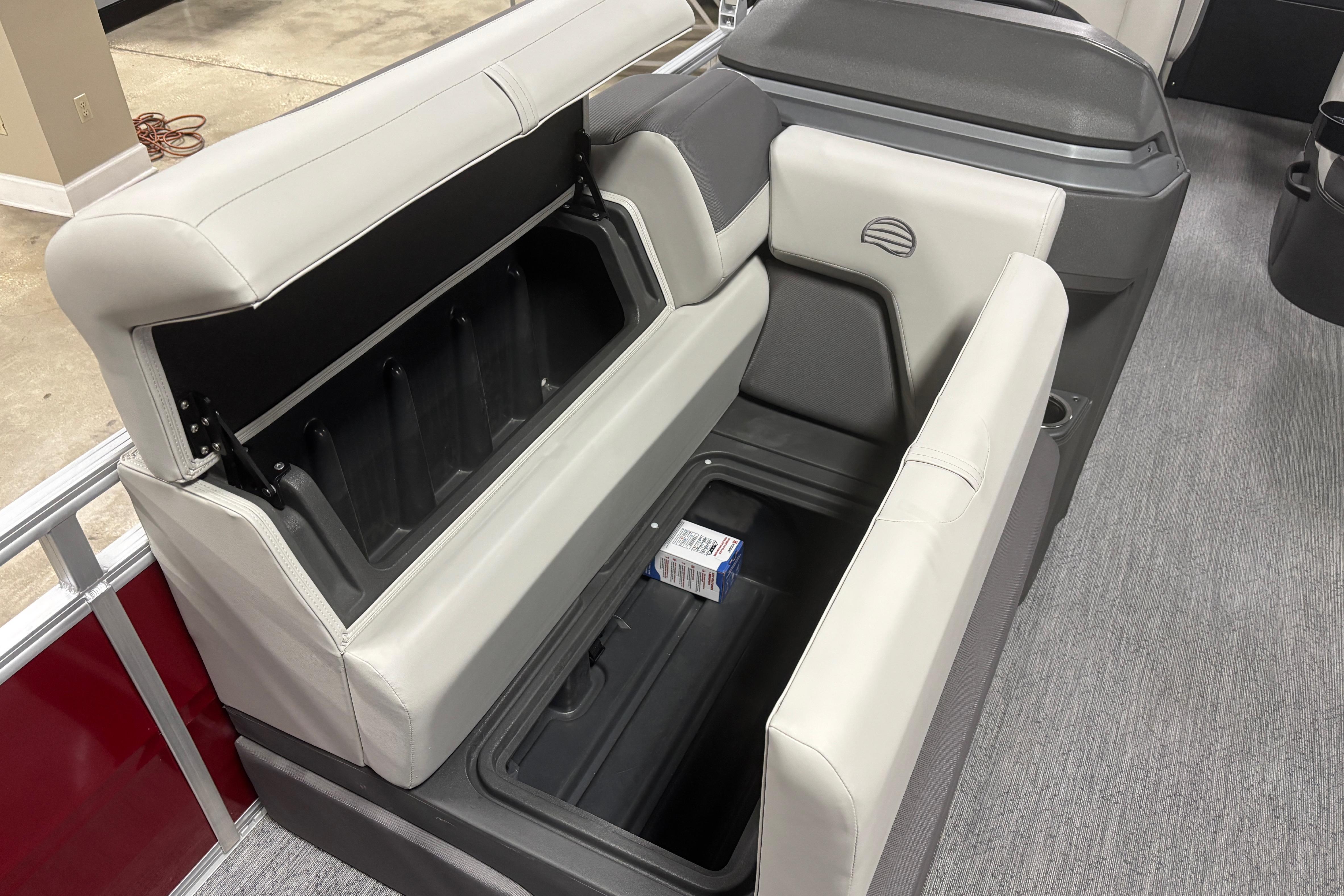2026 Sun Tracker Fishin' Barge 22 DLX interior storage compartment with open seat.