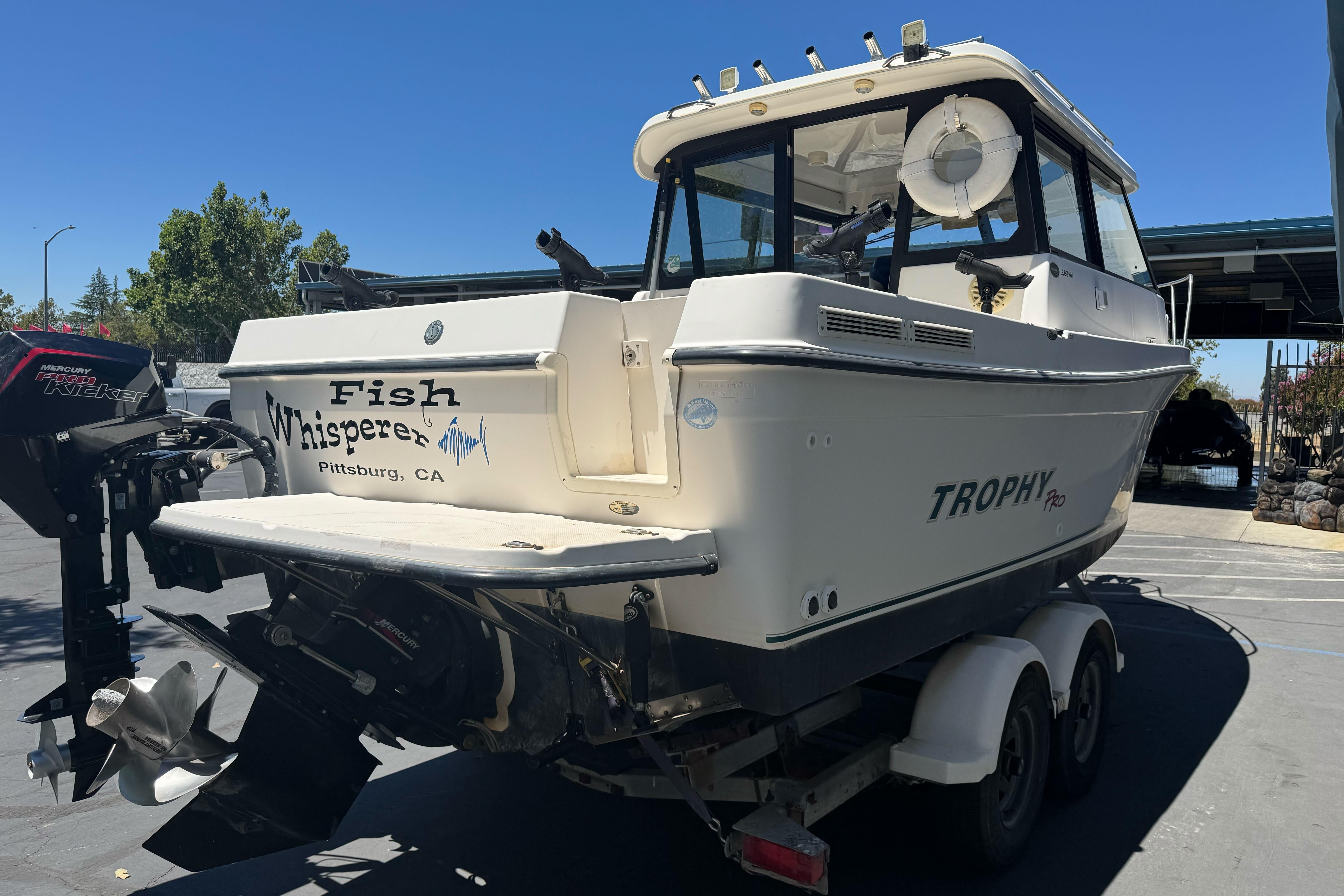 2004 Trophy 2359 WA boat on trailer, labeled "Fish Whisperer," parked outdoors in Pittsburg, CA.