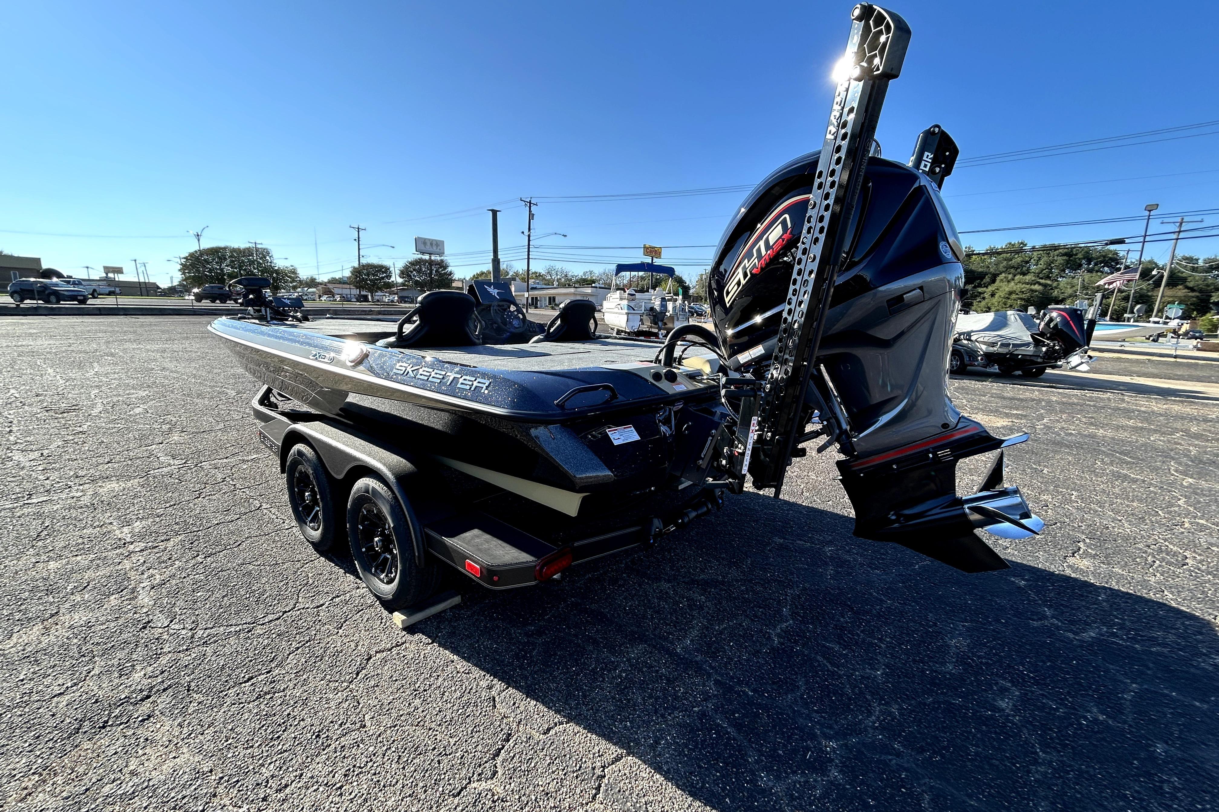 2026 Skeeter ZXE21 boat with powerful engine, parked on asphalt under clear blue sky.
