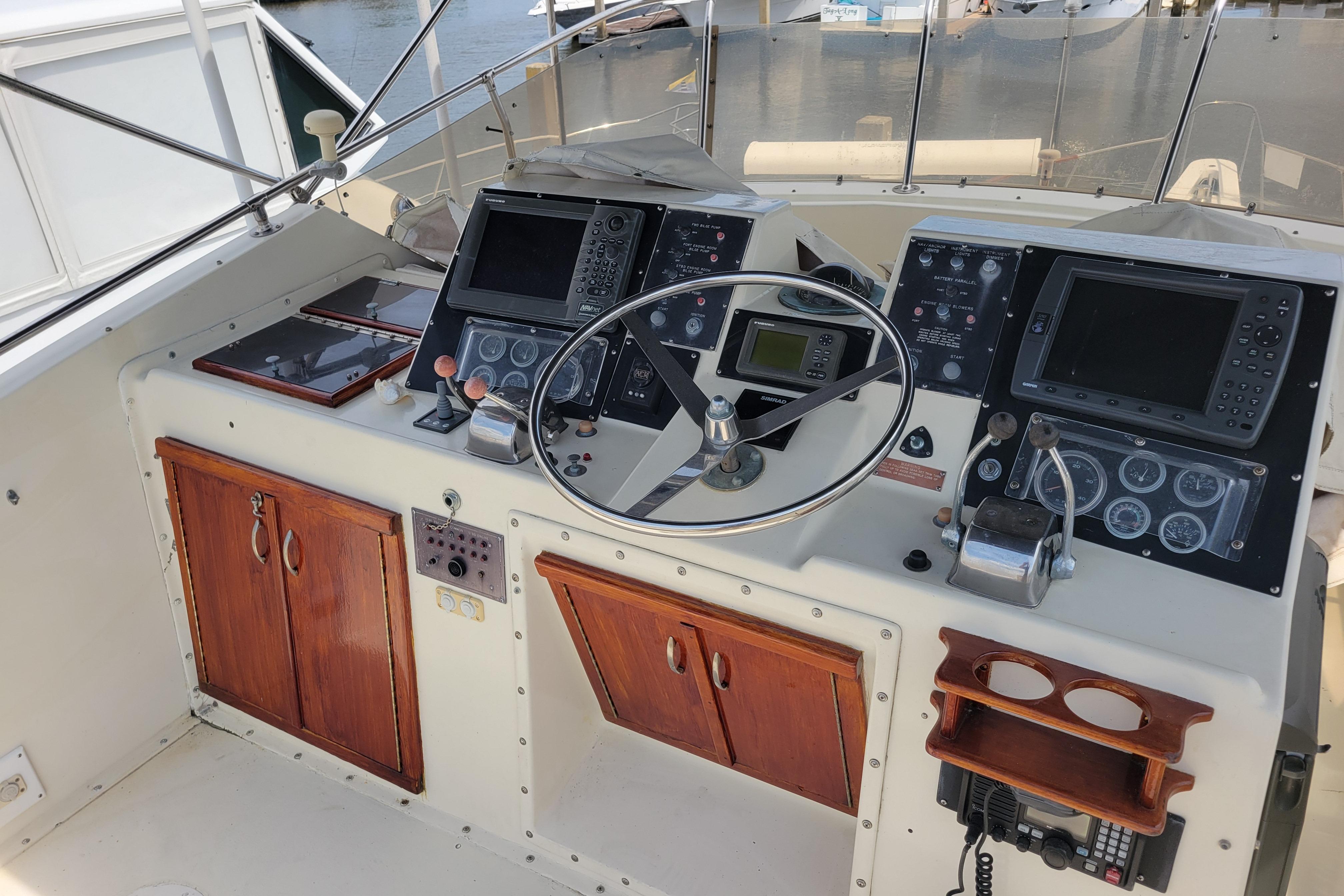 1980 Hatteras 53 Yacht Fisherman helm with navigation instruments and wooden cabinetry.
