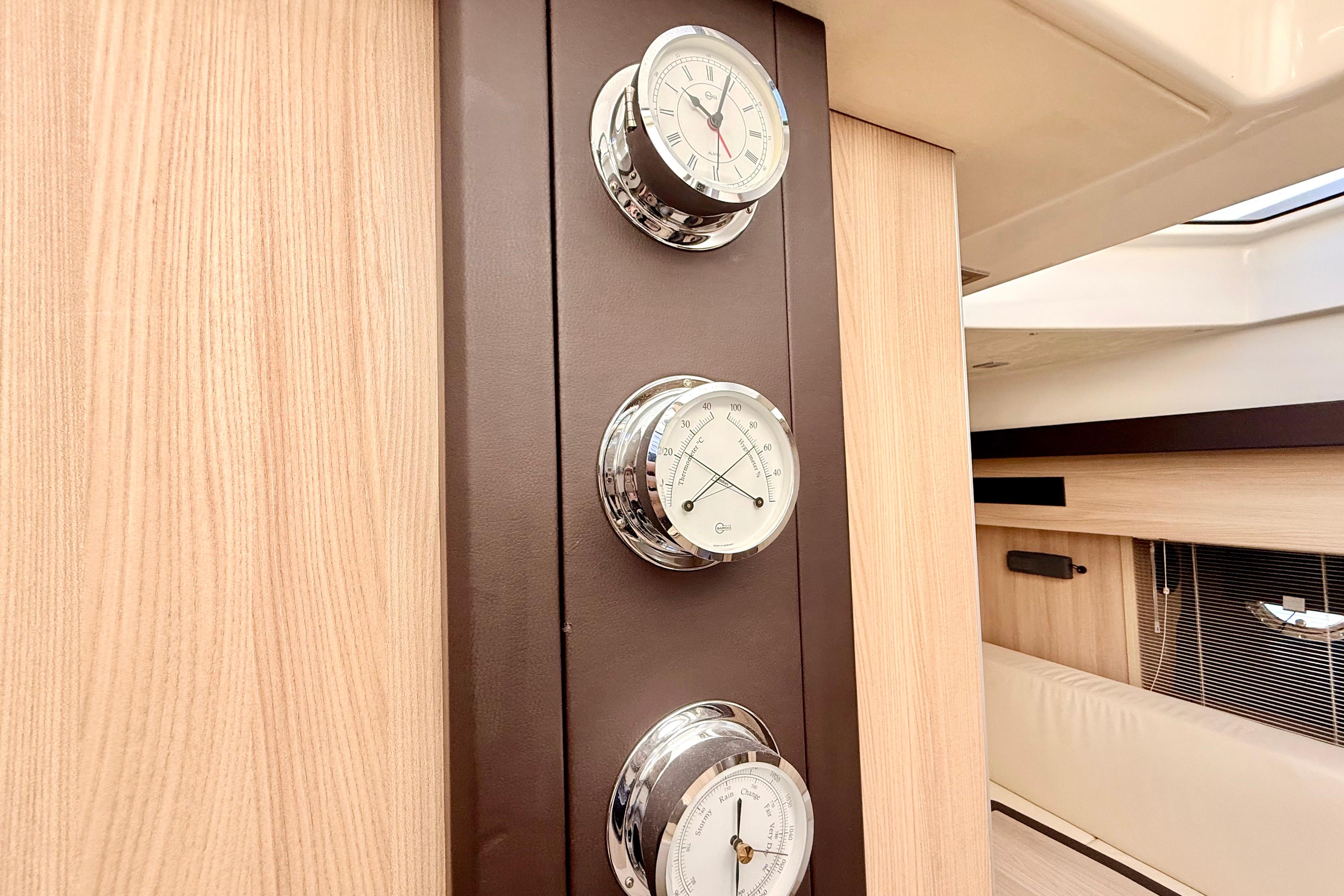 Interior of 2016 Cranchi M44 HT yacht with elegant wooden paneling and chrome gauges.