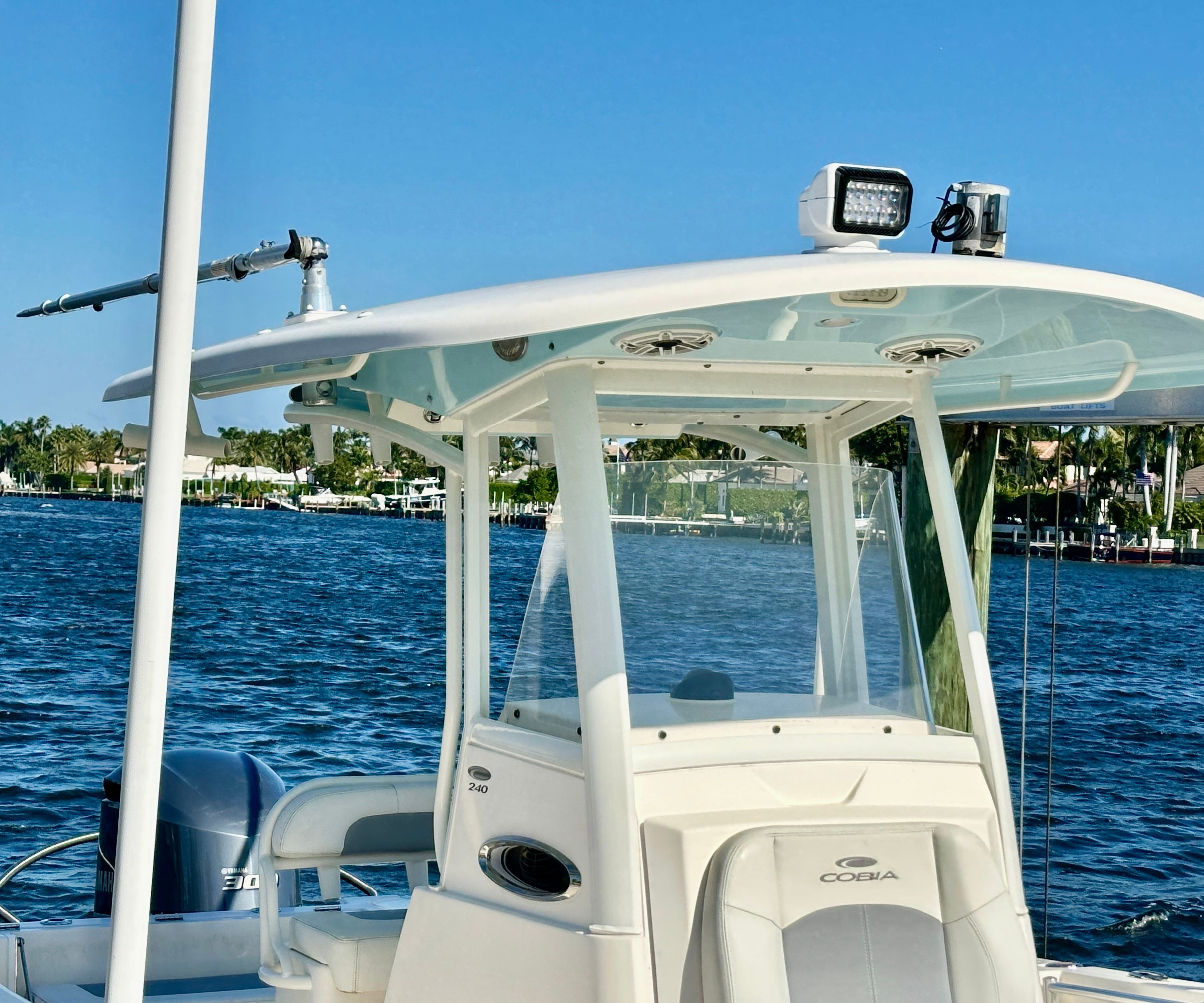A 2022 Cobia 240 Center Console boat on calm water with a blue sky.
