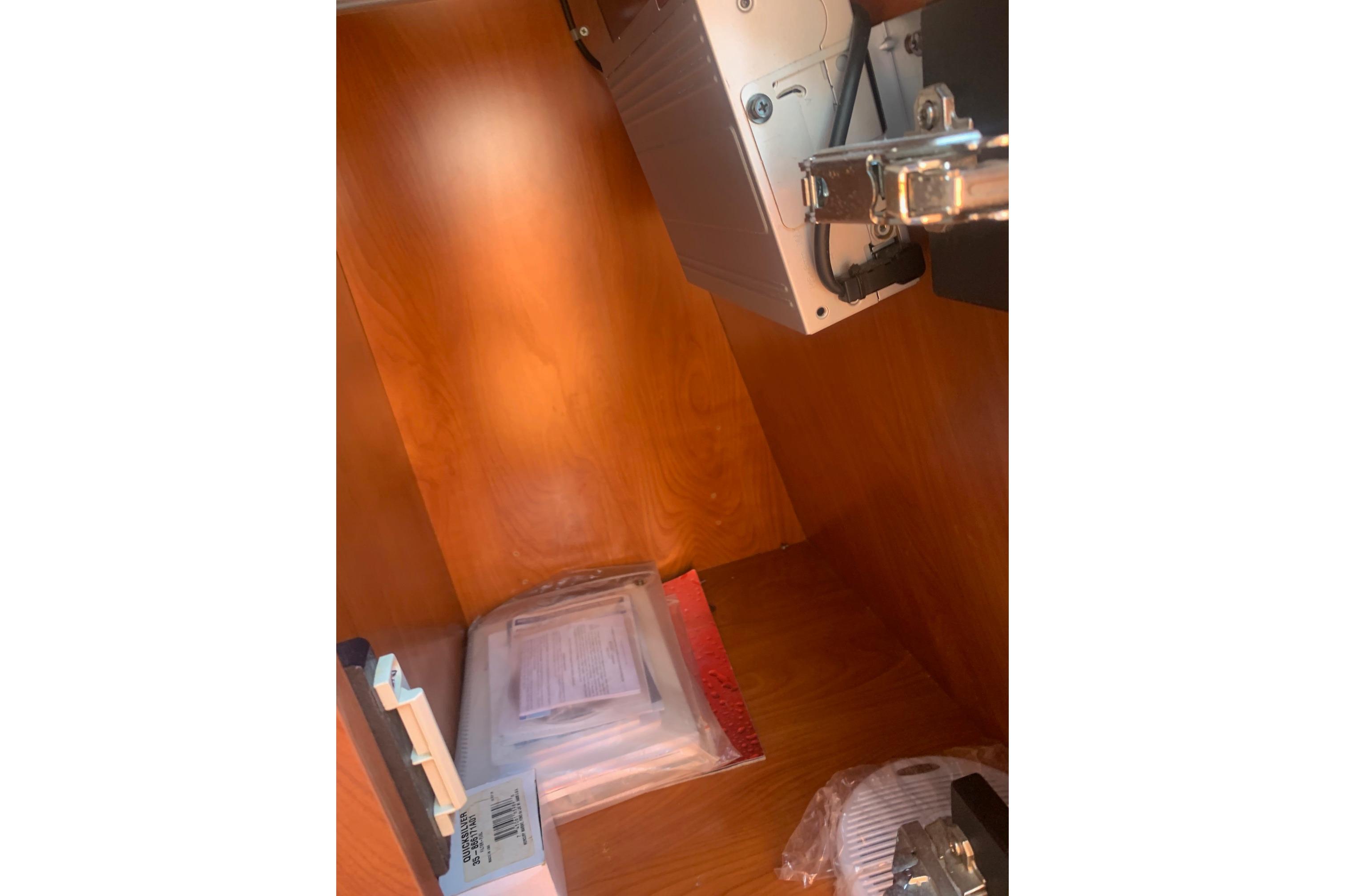 Interior view of a 2006 Rinker 282 Captiva Cuddy storage compartment with equipment and documents.