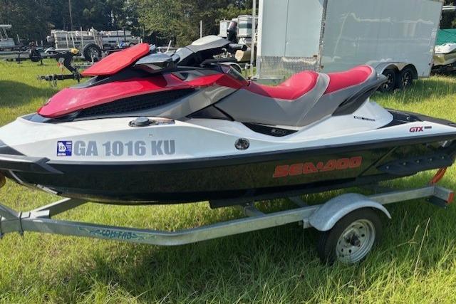 2010 Sea-Doo GTX 155 jet ski on trailer, red and black, parked on grass.
