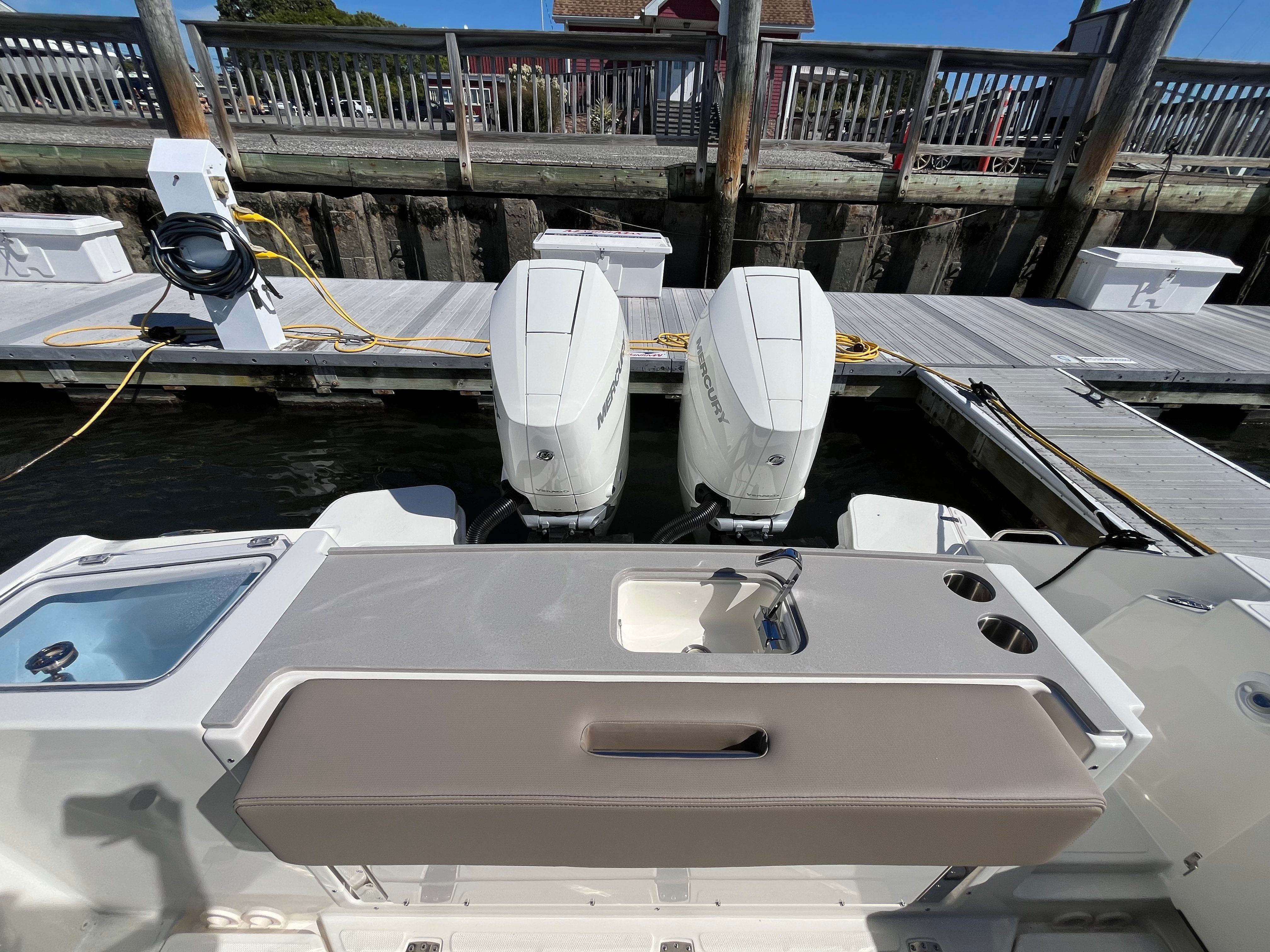 The image shows the stern of a Boston Whaler 330 Vantage with twin outboard engines at a dock.
