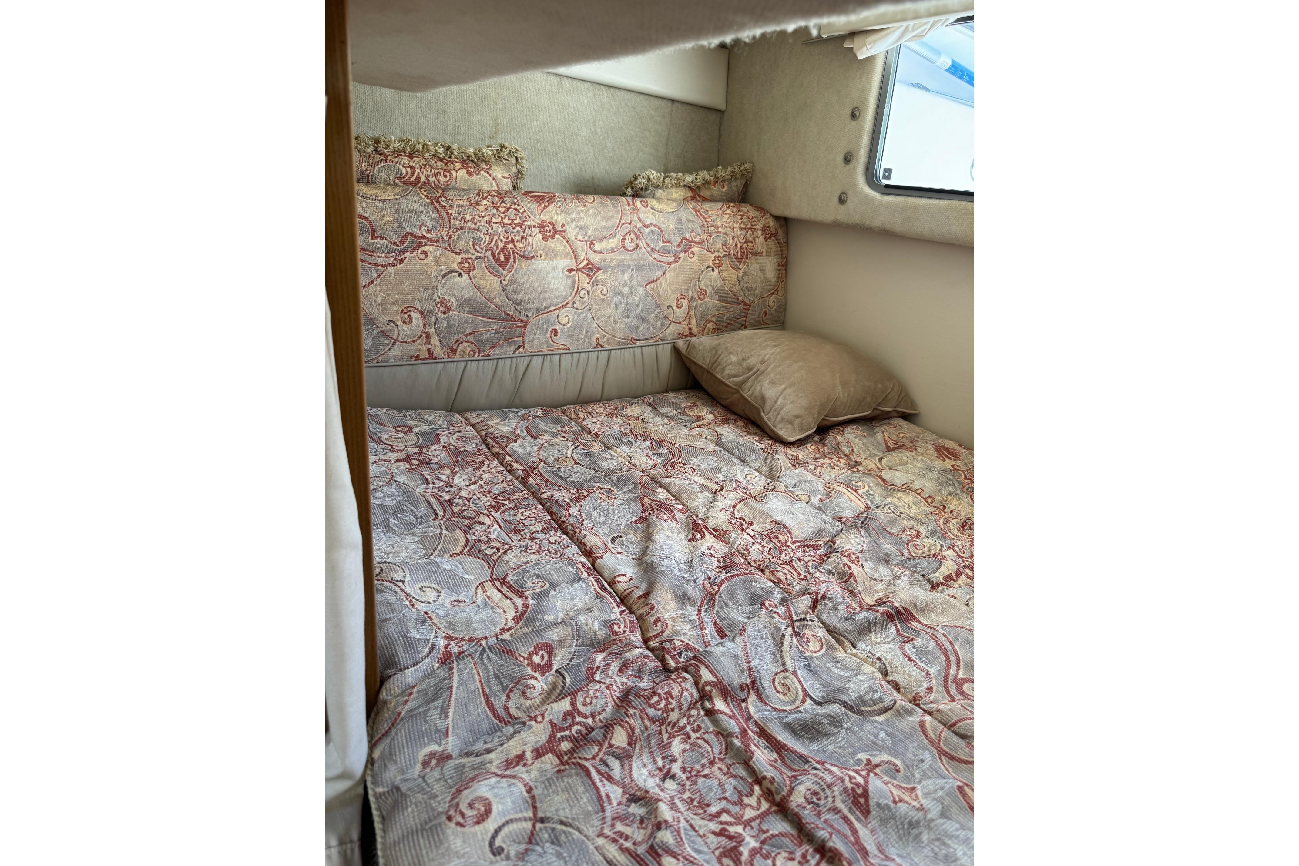 Cozy cabin bed in 2000 Maxum 2400 SCR boat with patterned bedding.