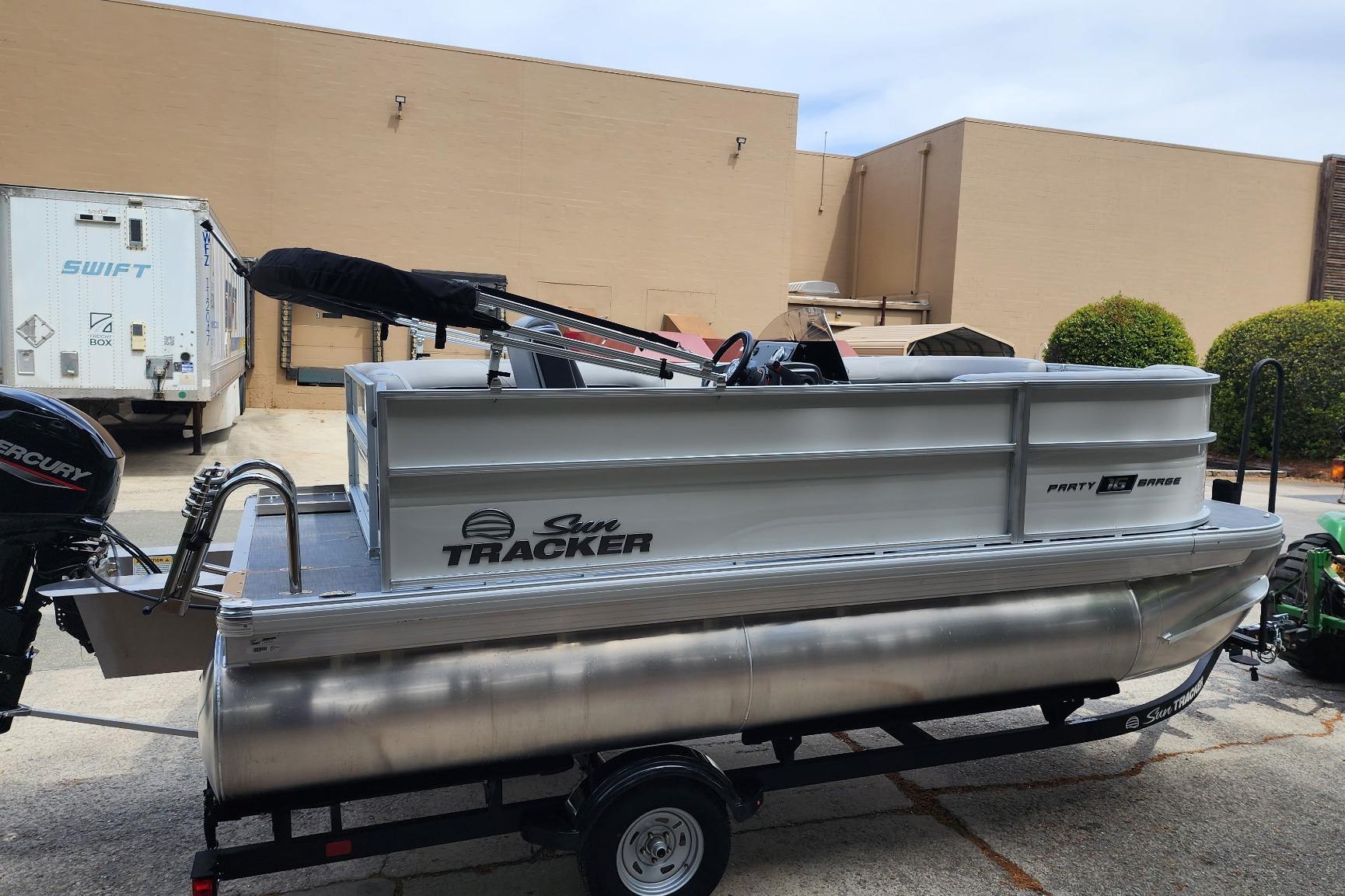 2026 Sun Tracker Party Barge 16 DLX pontoon boat on trailer, parked outdoors.