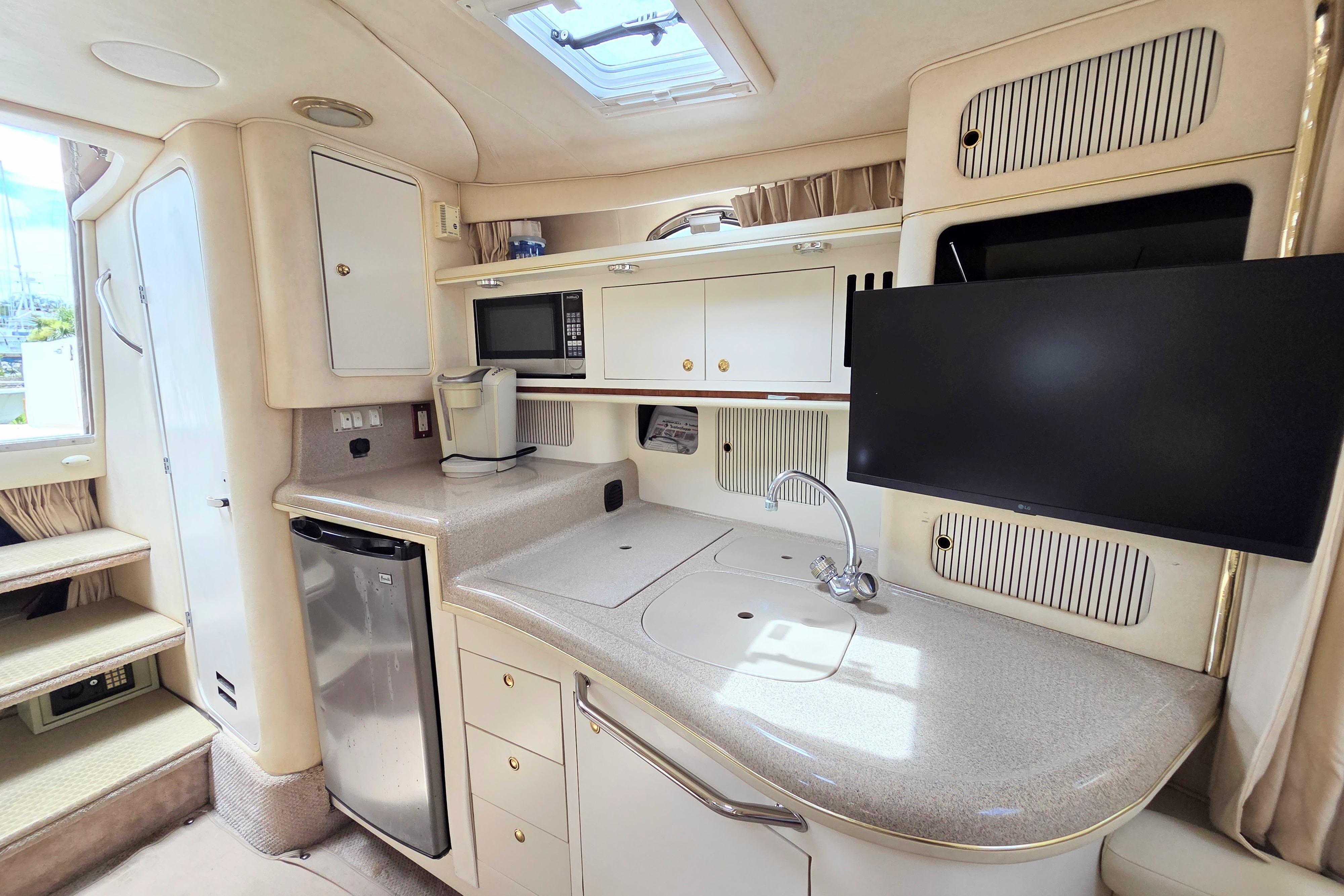 Luxurious 2000 Sea Ray 340 Sundancer yacht interior with kitchenette, TV, and modern amenities.