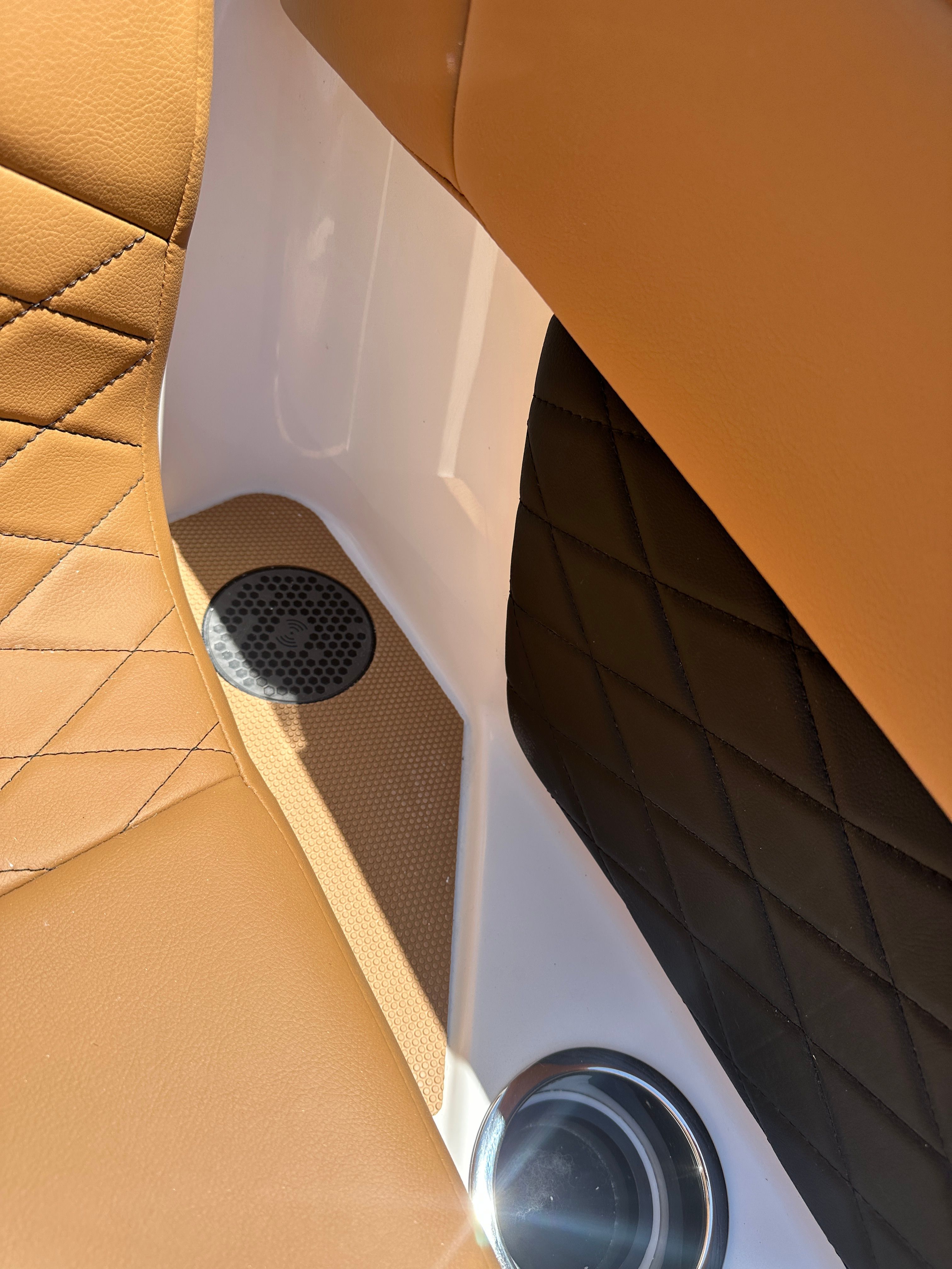 Close-up of a boat seat with brown leather and a speaker.