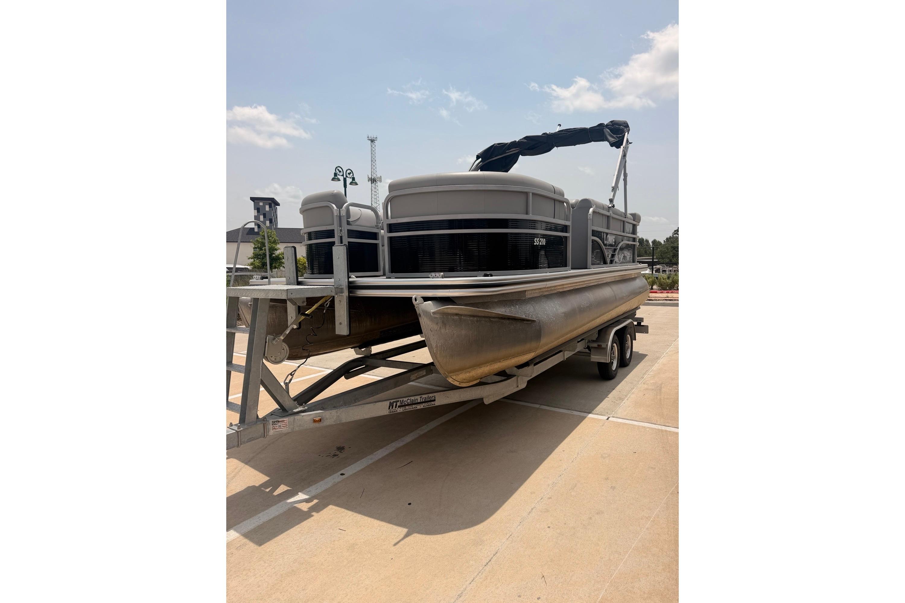 2021 Lowe SS 210 pontoon boat on trailer under clear sky.