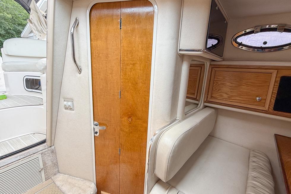 1999 Sea Ray 290 Sundancer cabin interior with wooden door and seating area.