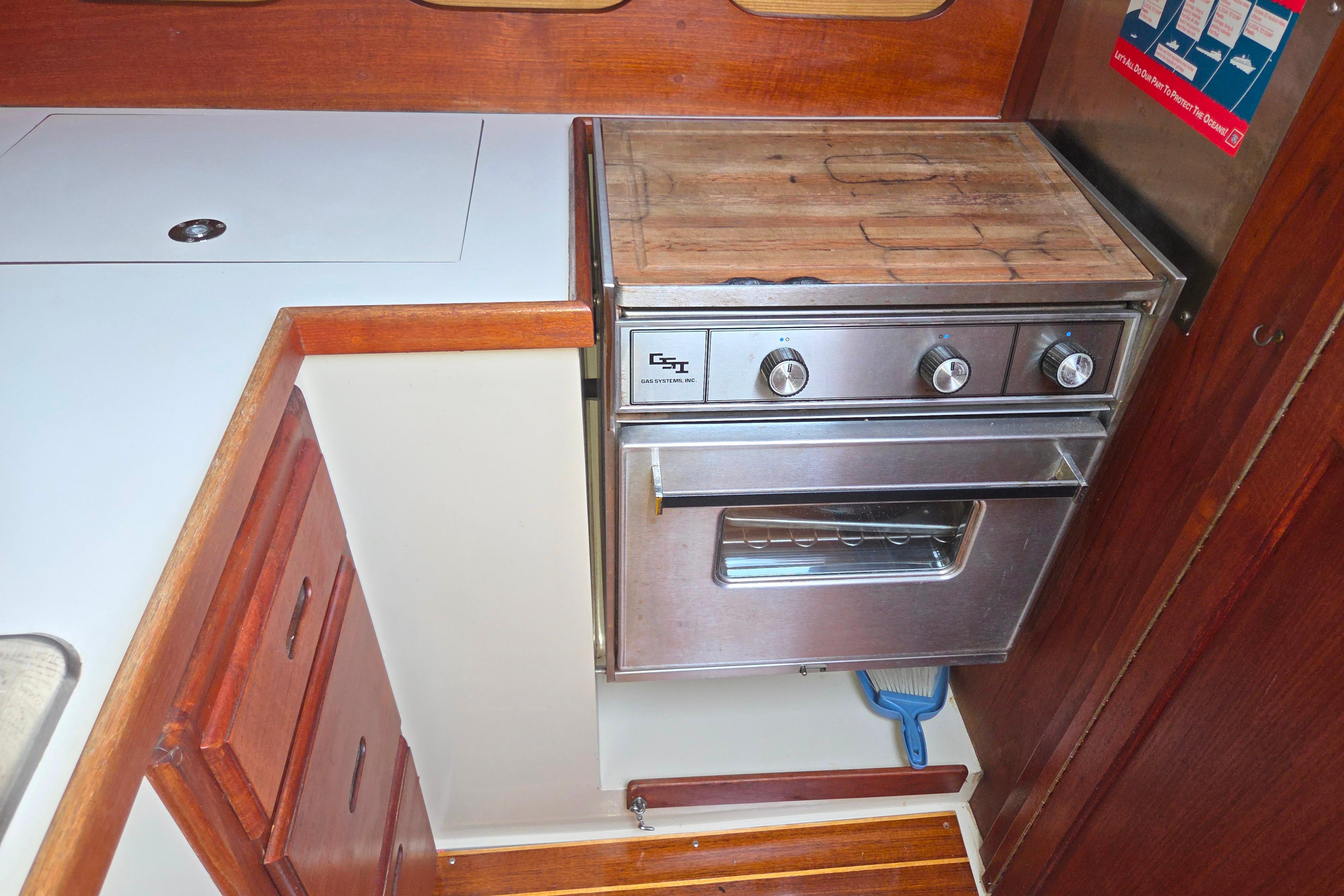 Galley kitchen in 1986 Catalina 355 sailboat with stove and wooden cabinetry.