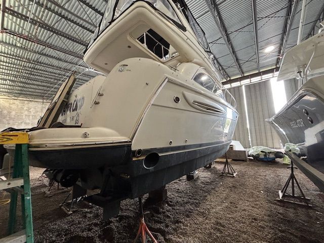 A 2004 Meridian 341 Sedan yacht is supported on stands in a warehouse.