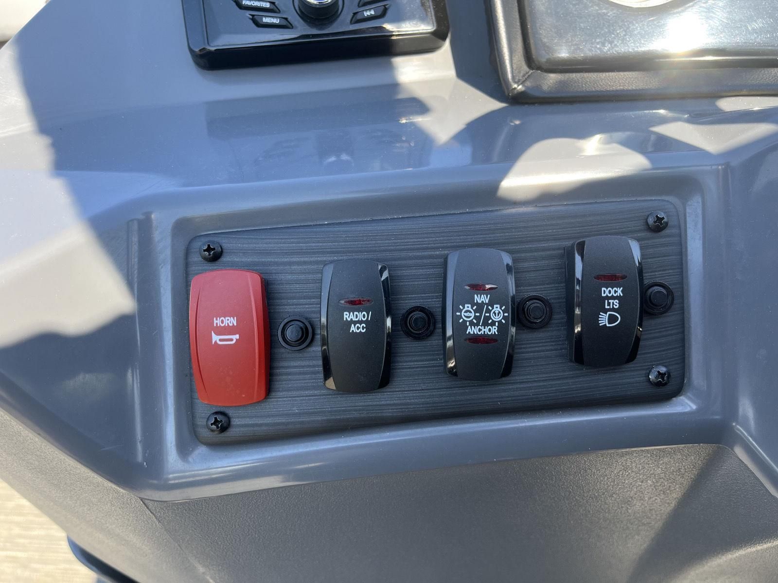 Close-up of a boat control panel with switches for horn, radio, anchor, and dock lights.