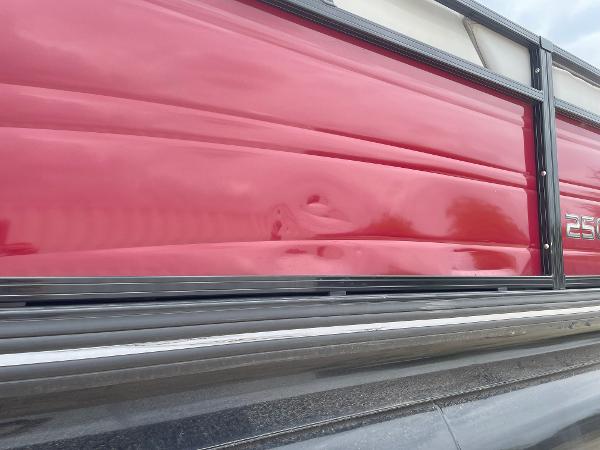 2023 Regency 250DL3 boat with red exterior paneling and visible dent.