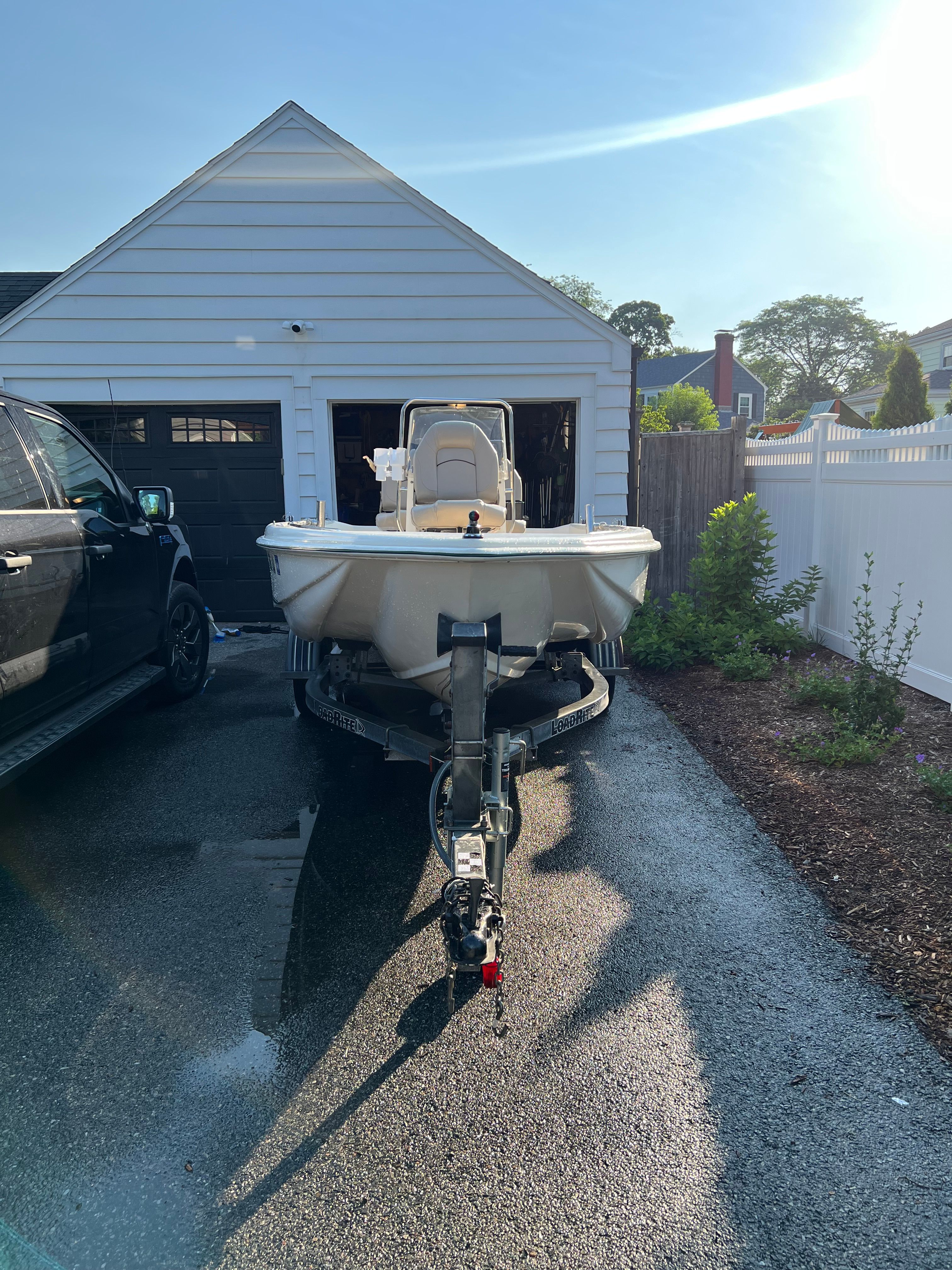 A 2001 Scout 151 Sportfish boat on a trailer in a driveway.