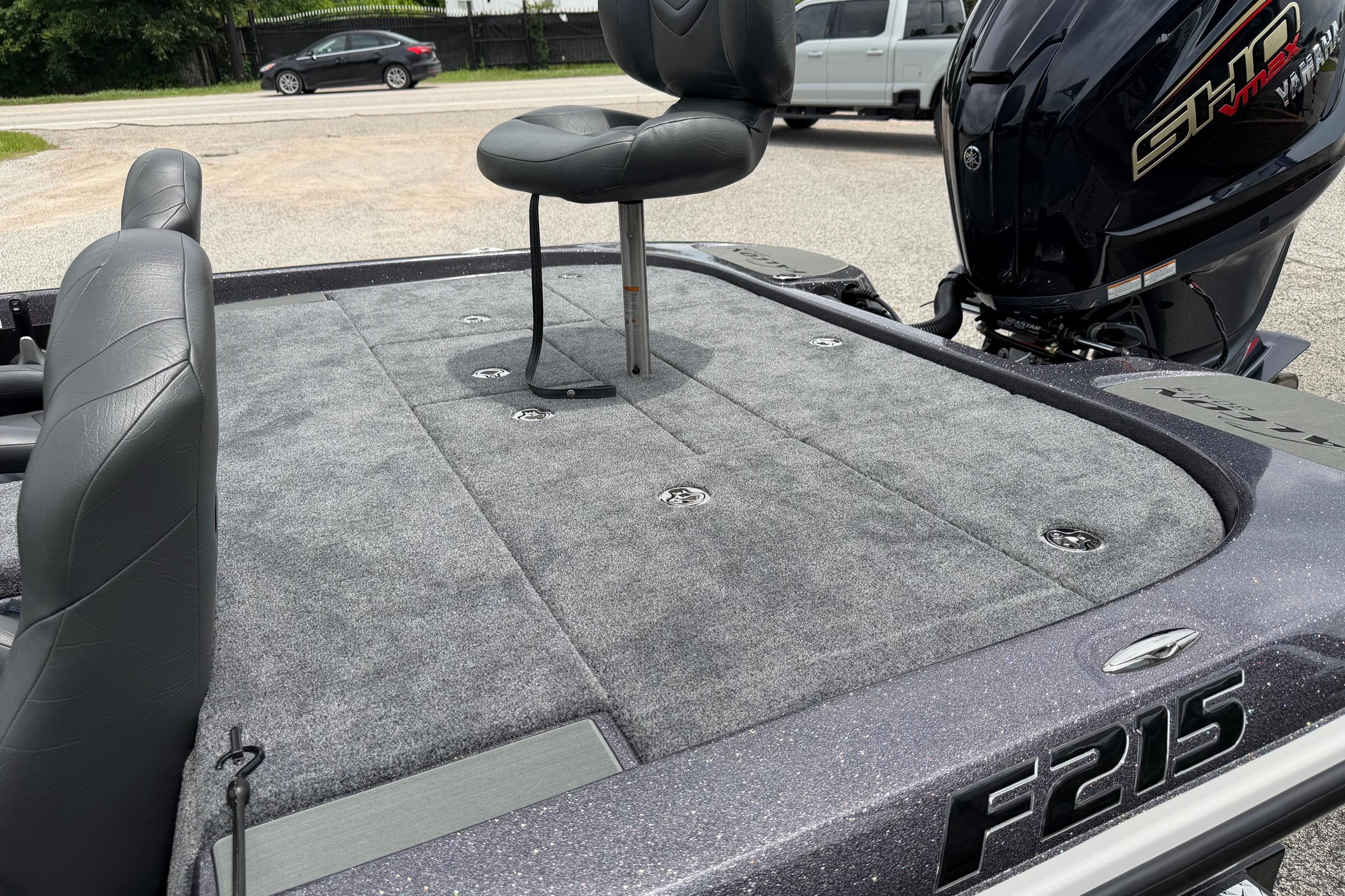 2027 Falcon Boats F215 fishing deck with seating and motor, parked outdoors.