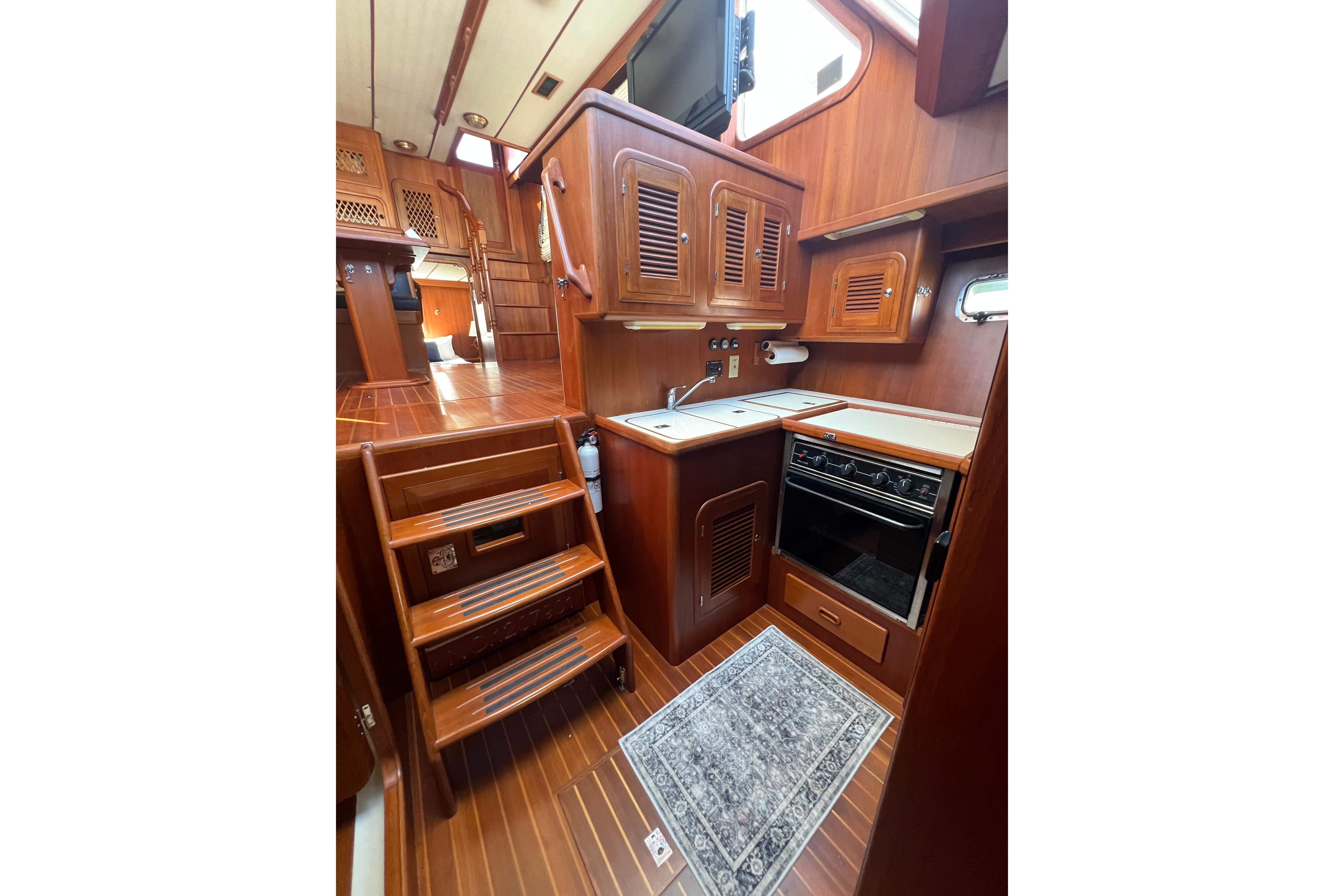 Interior of 2007 Heritage East 36 Sundeck Trawler with wooden cabinetry and compact kitchen.