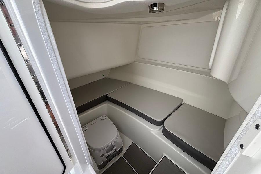 2027 Sea Ray SDX 230 Outboard cabin interior with seating and portable toilet.