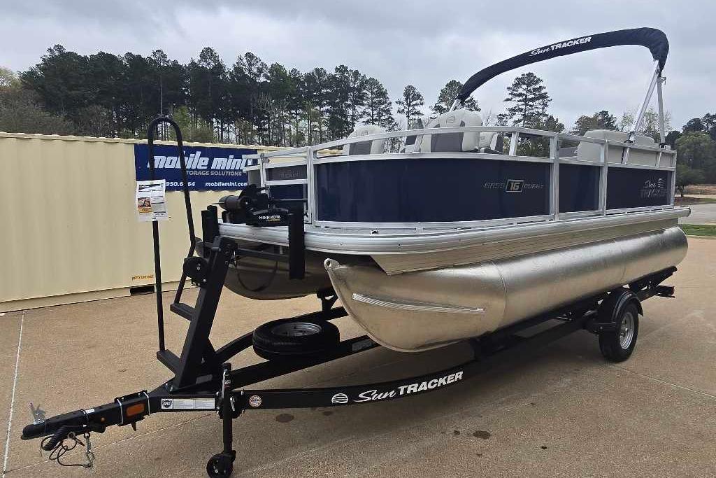 2026 Sun Tracker Bass Buggy 16 XL Select pontoon boat on trailer, parked outdoors.