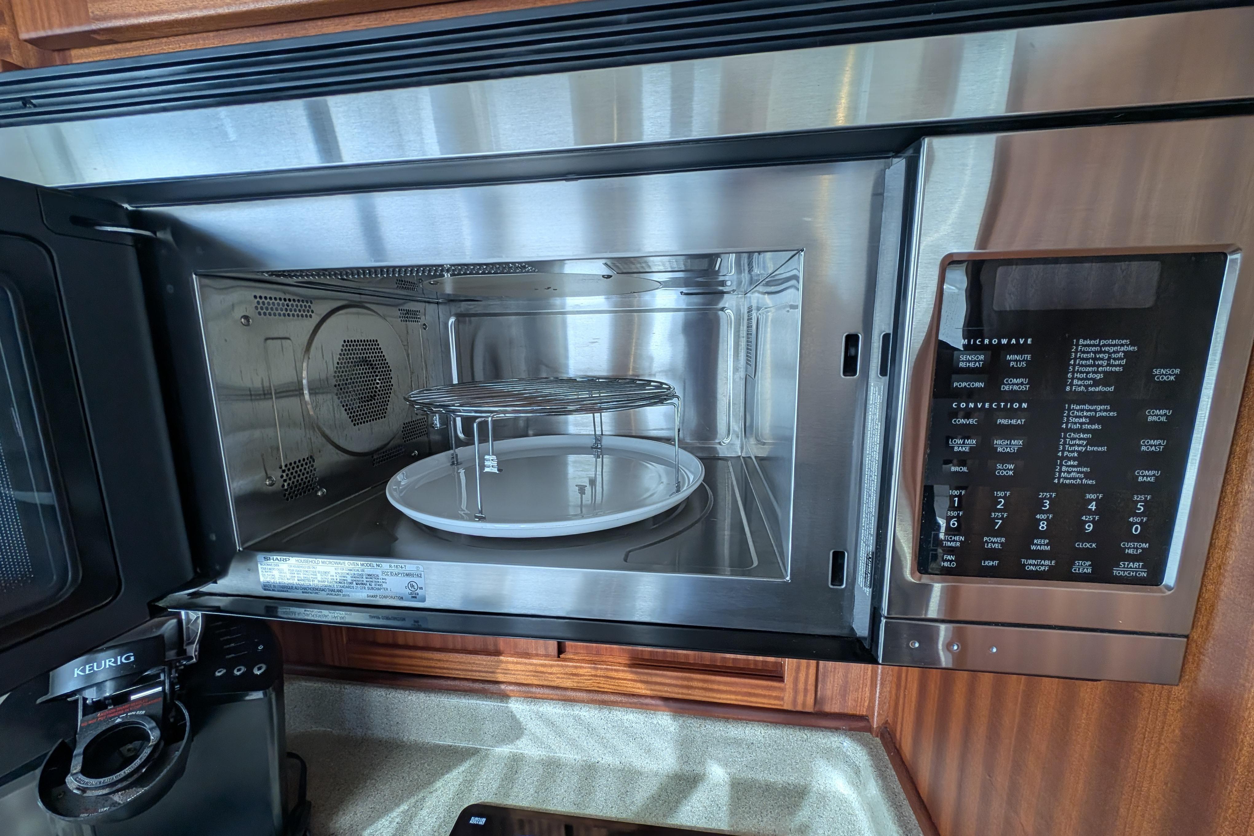 Open microwave oven in 2015 American Tug 435 kitchen, with control panel and Keurig coffee maker nearby.