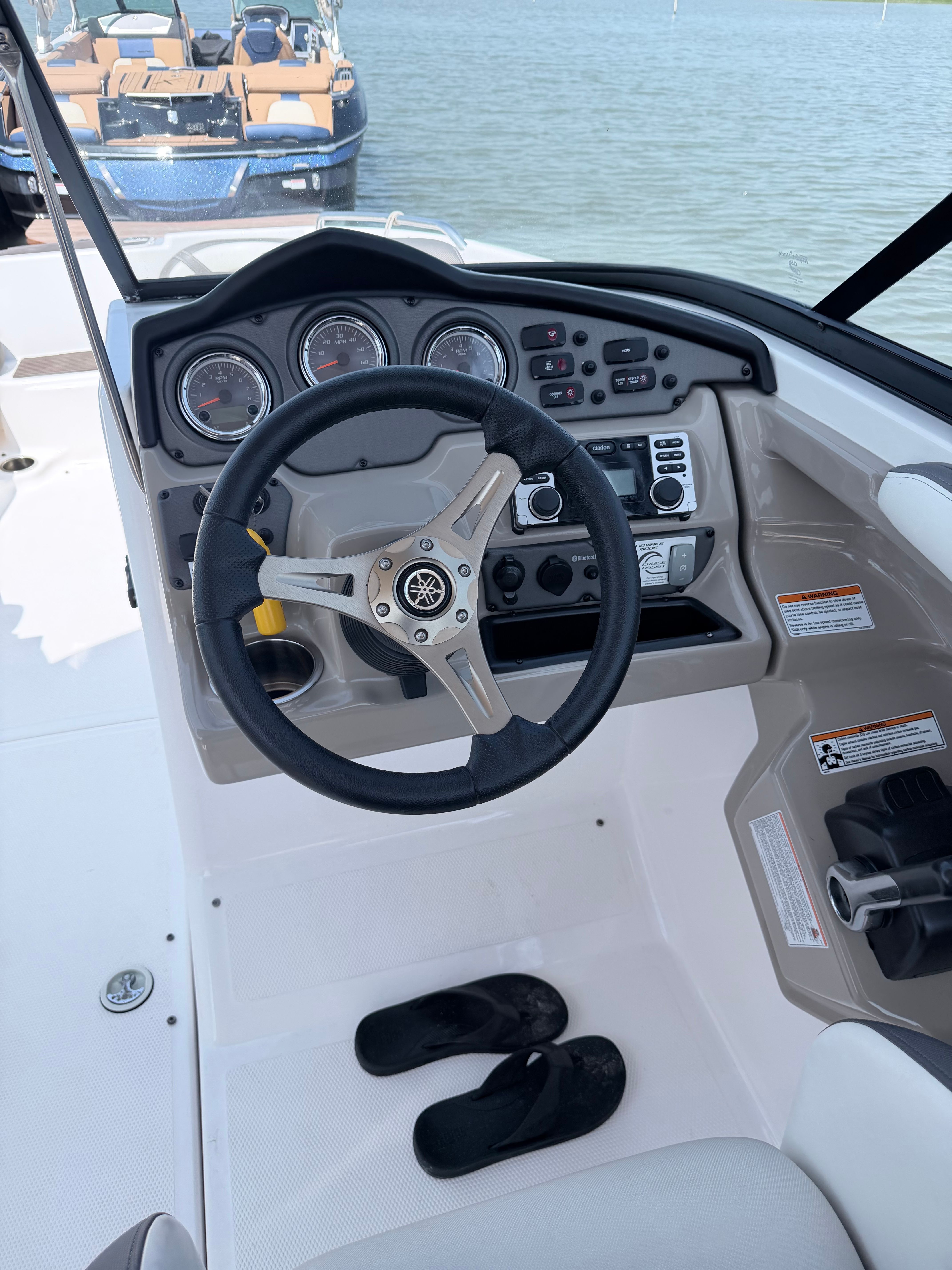 The image shows the helm of a 2014 Yamaha 242 Limited S boat with a sleek steering wheel.
