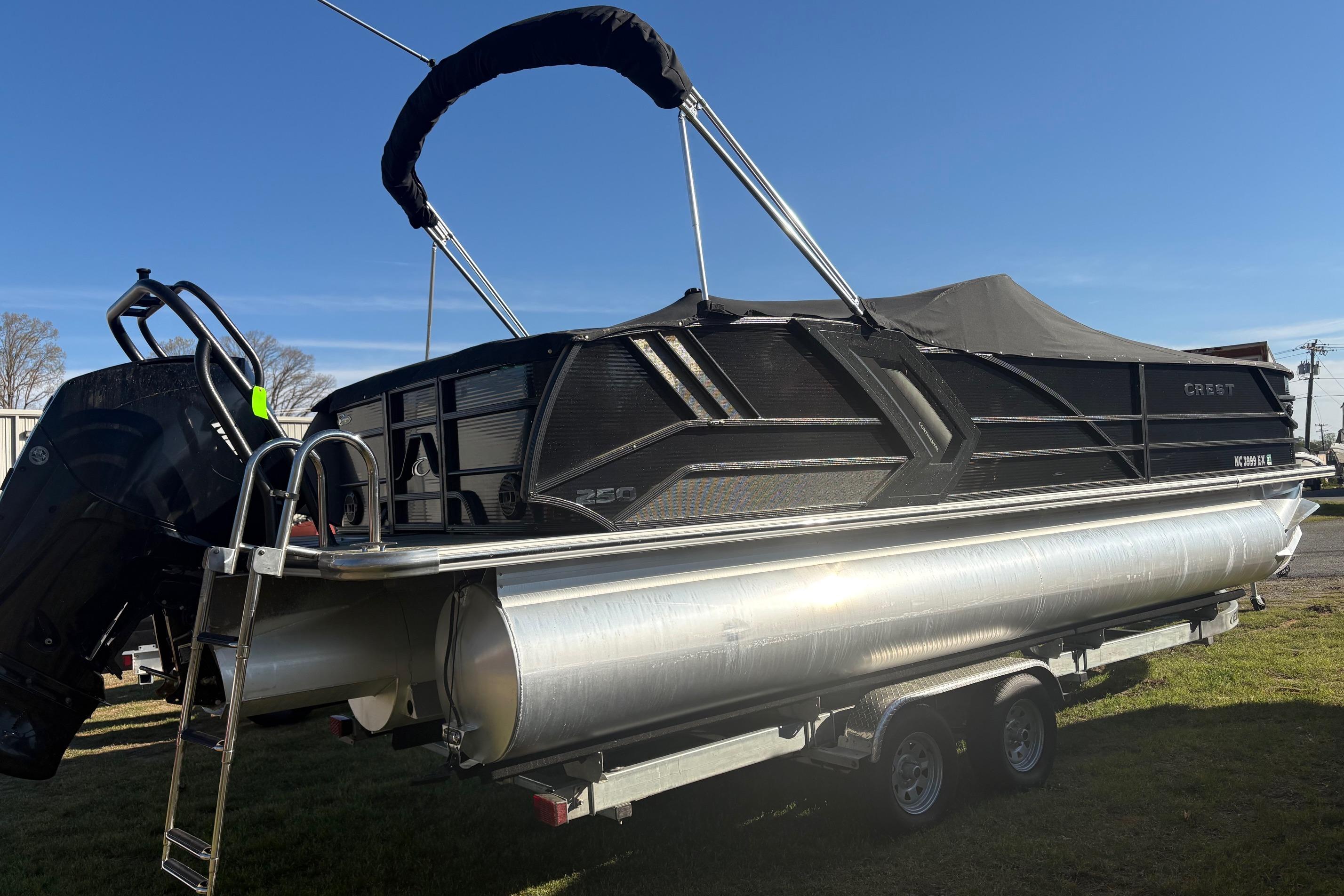 2022 Crest Continental 250 pontoon boat on trailer, featuring sleek black design and powerful outboard motor.