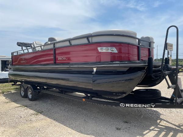 2023 Regency 250 DL3 pontoon boat on trailer, red and black design, parked outdoors.