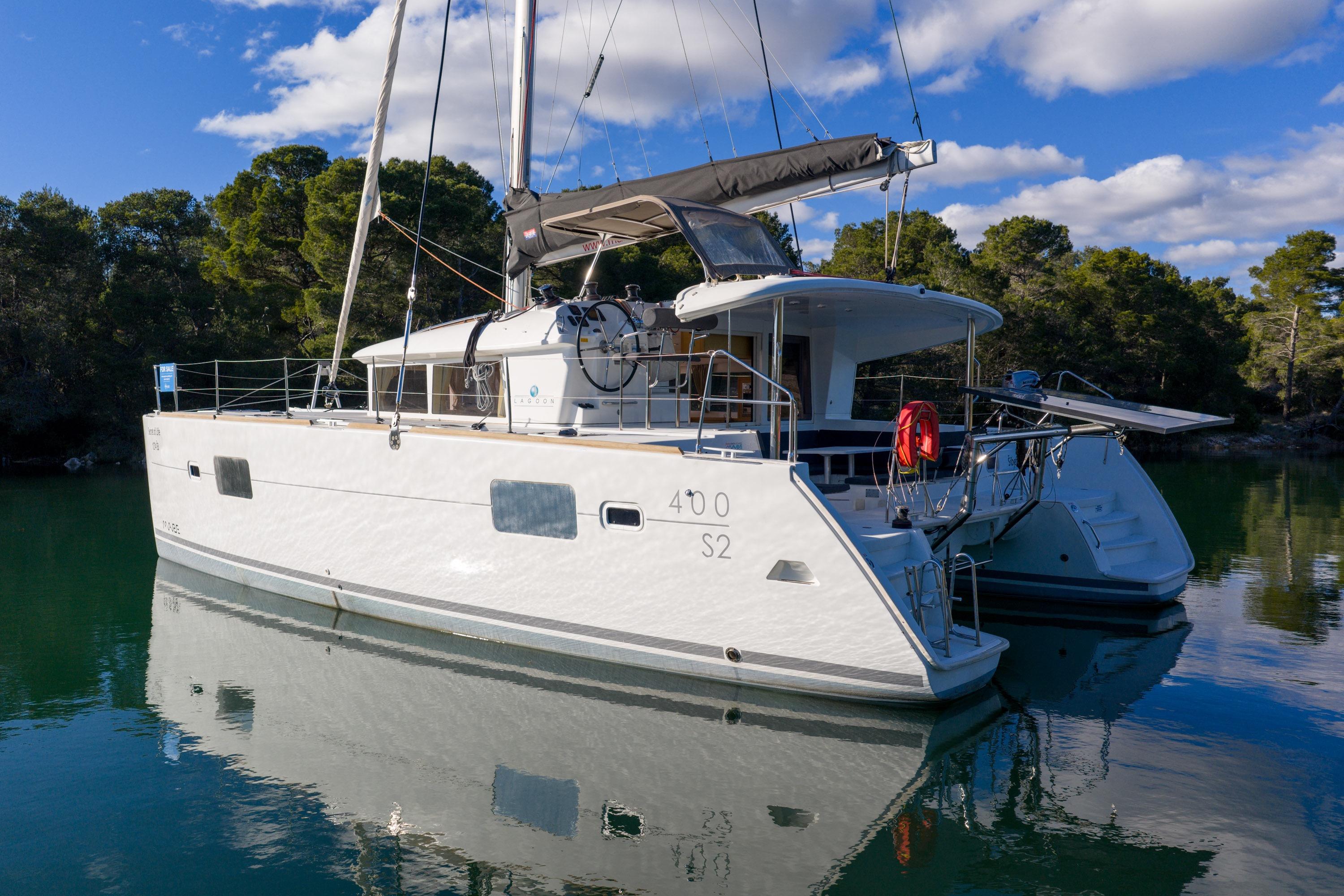 2015 Lagoon 400 S2 catamaran docked in serene waters, surrounded by lush greenery.