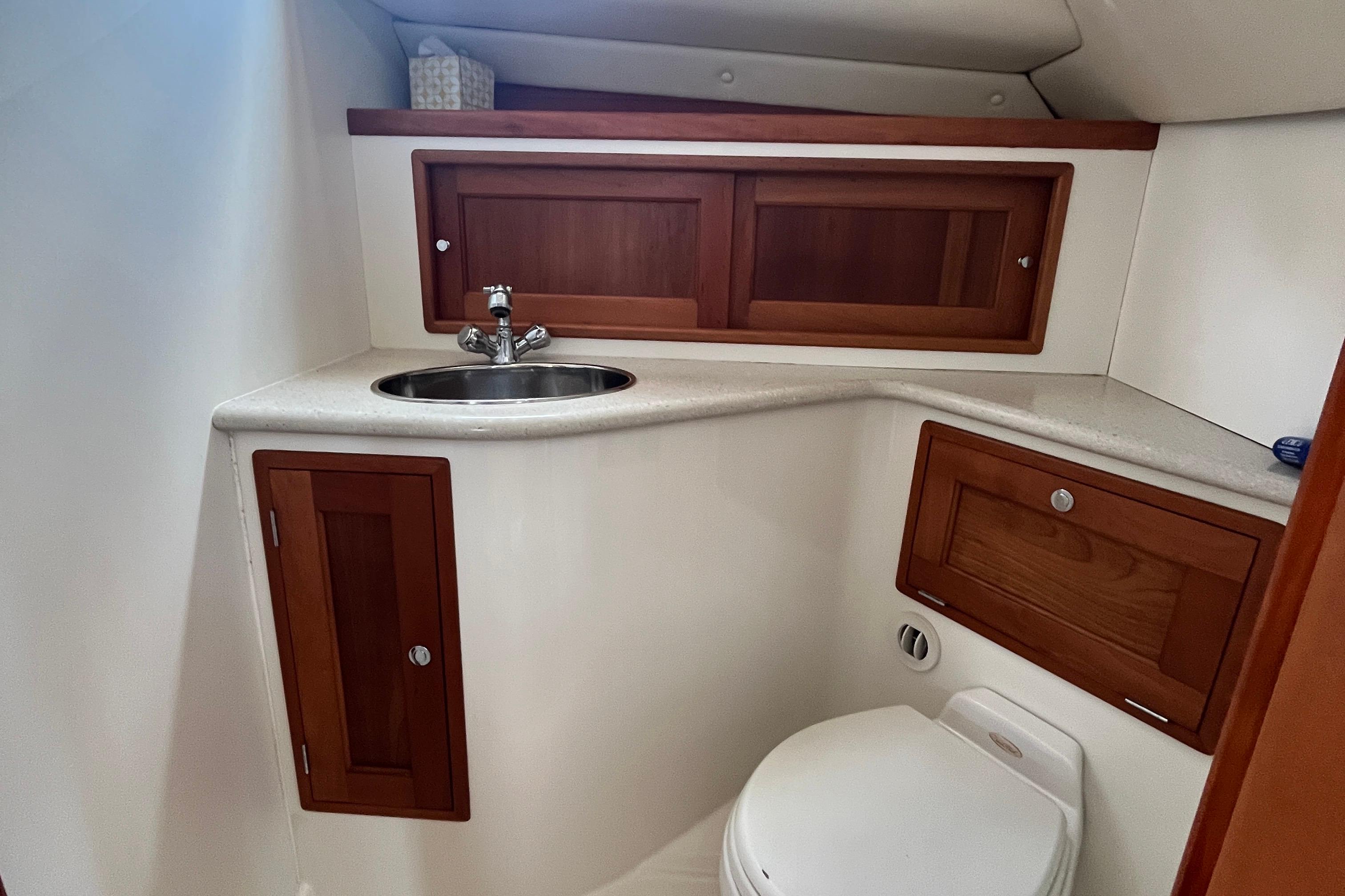 Compact bathroom in 2006 MJM 34z boat with wooden cabinets and stainless steel sink.