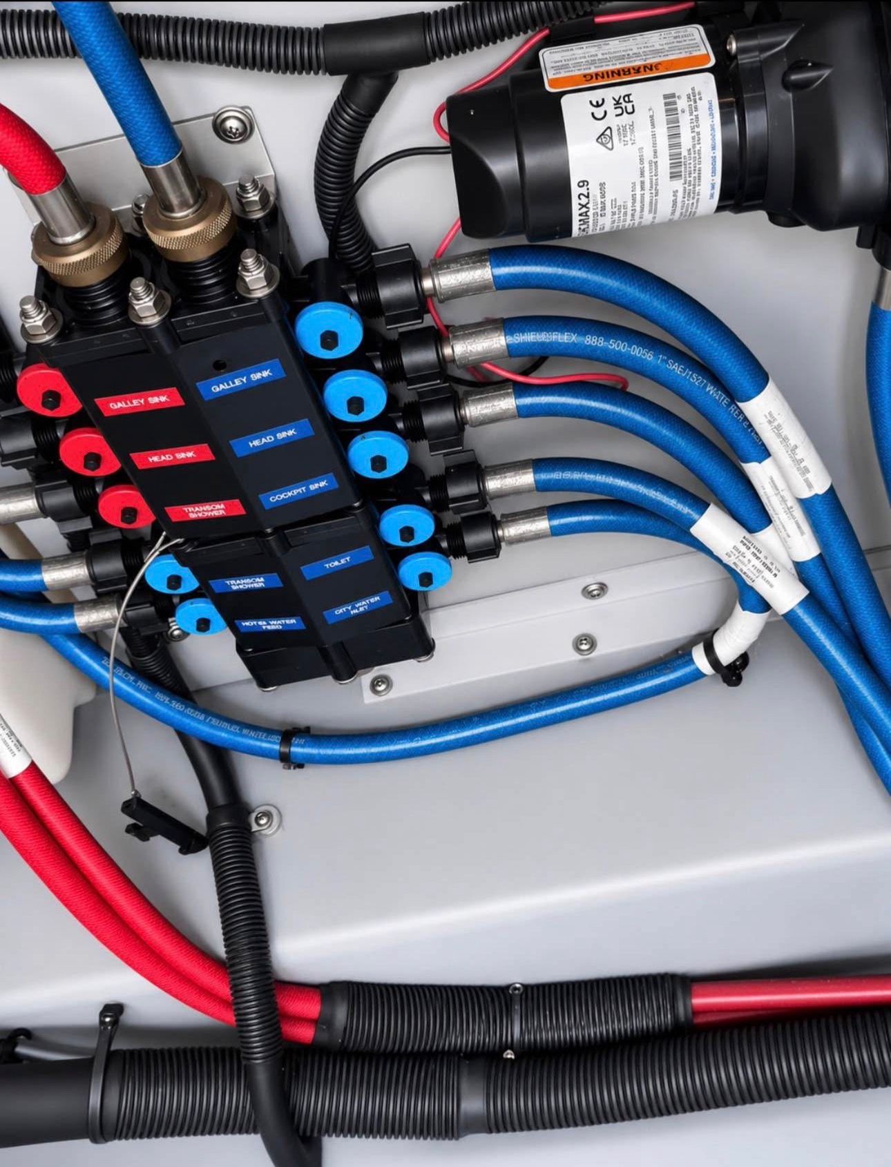 Close-up of colored hoses and valves in a boat engine compartment.