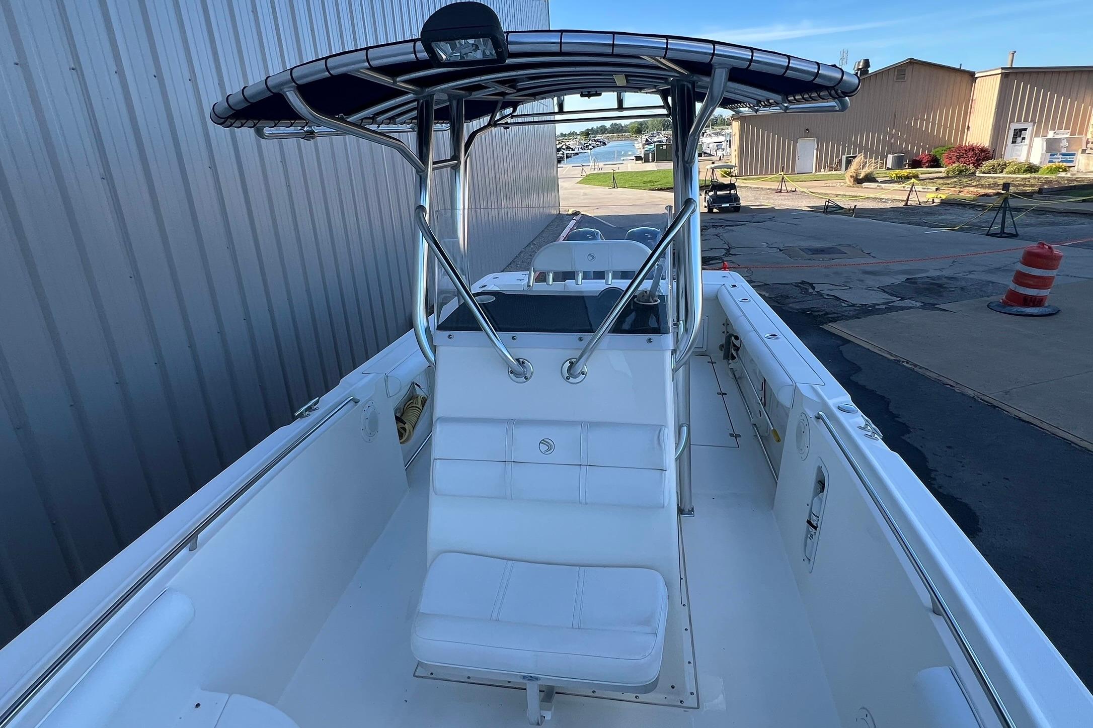 2006 Edgewater 245CC boat with T-top, docked near industrial buildings.