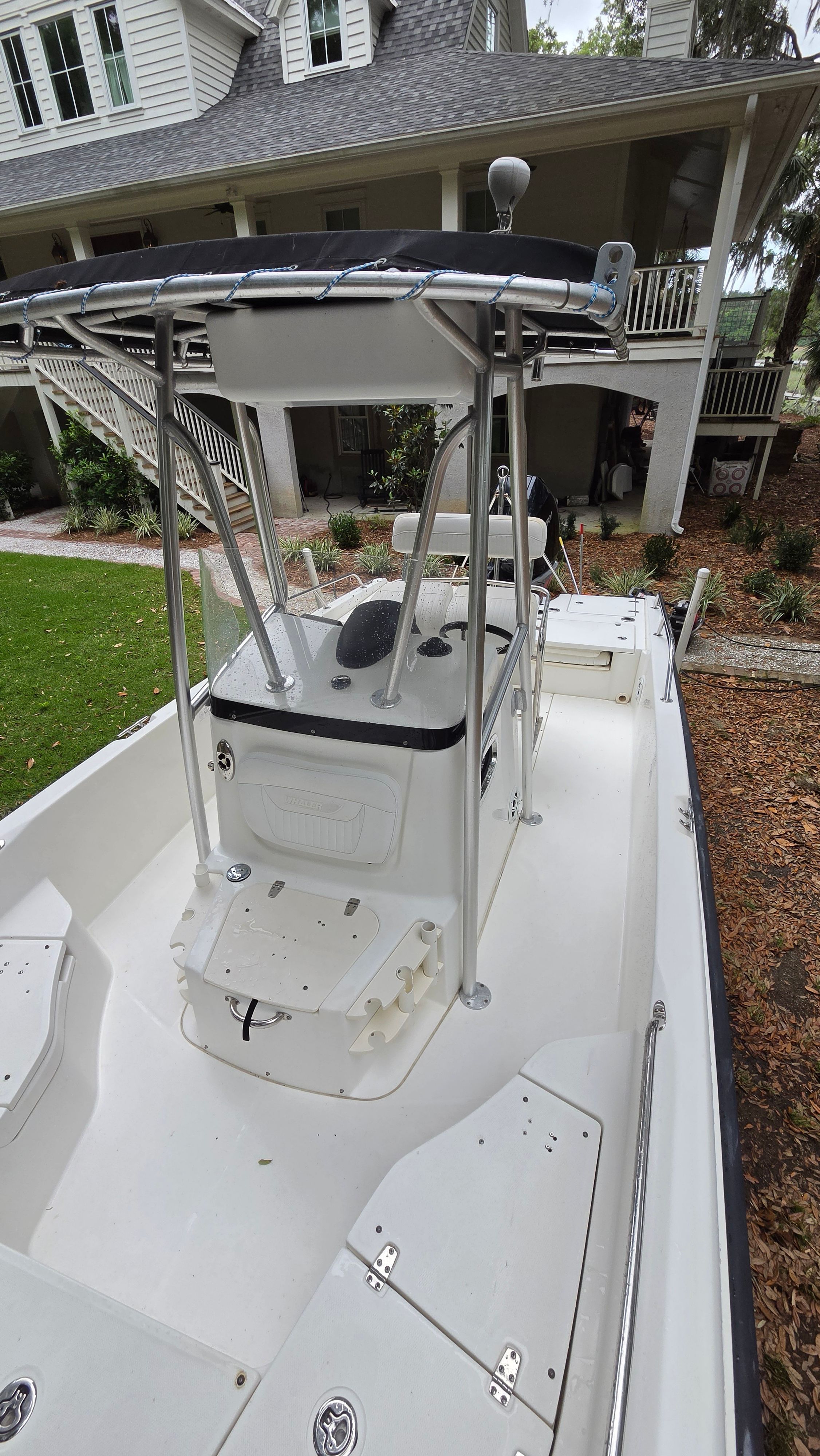 A 2008 Boston Whaler 230 Dauntless on a trailer in front of a house.