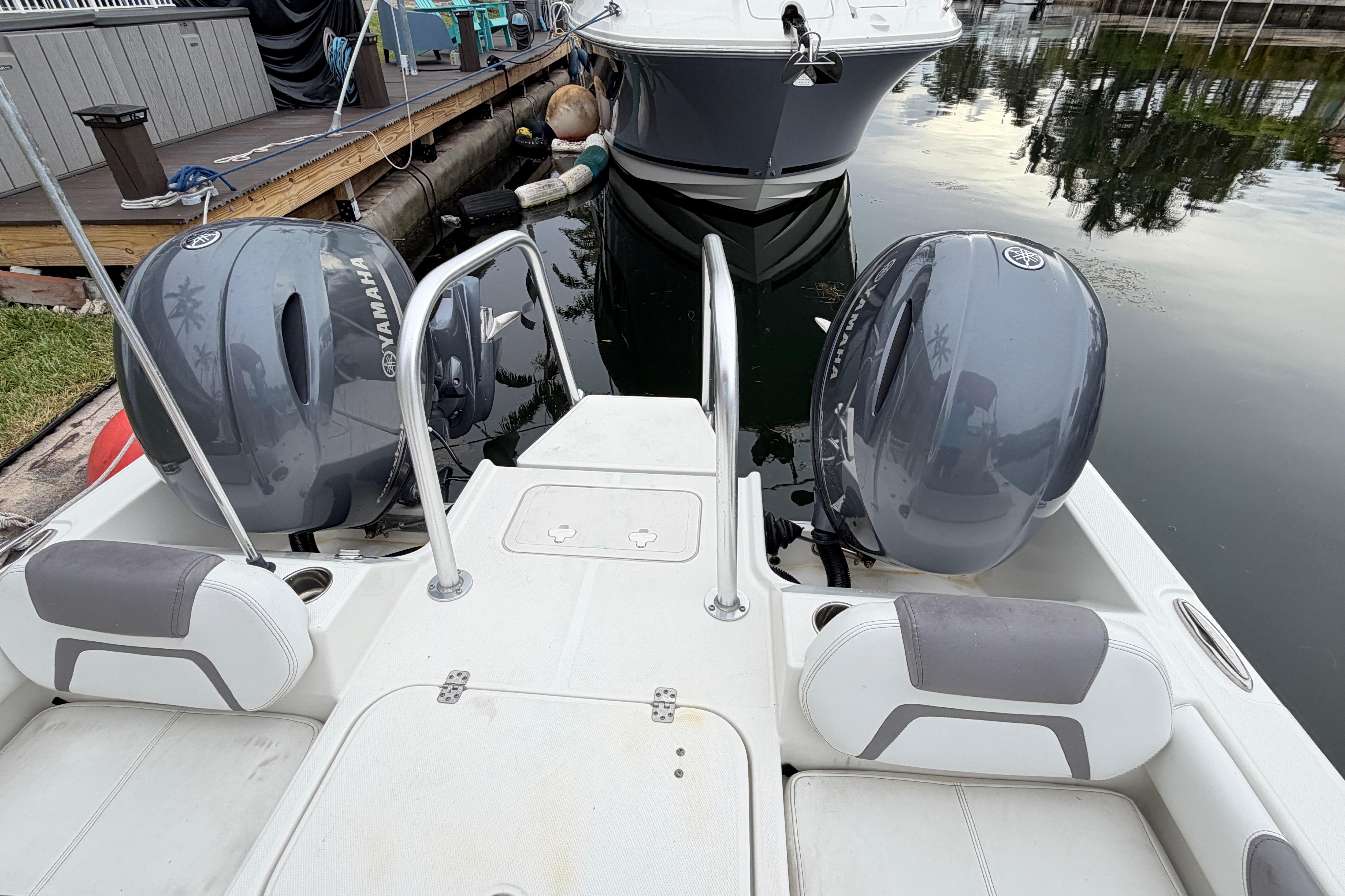 2019 World Cat 230 DC boat with twin Yamaha outboard engines docked by the water.