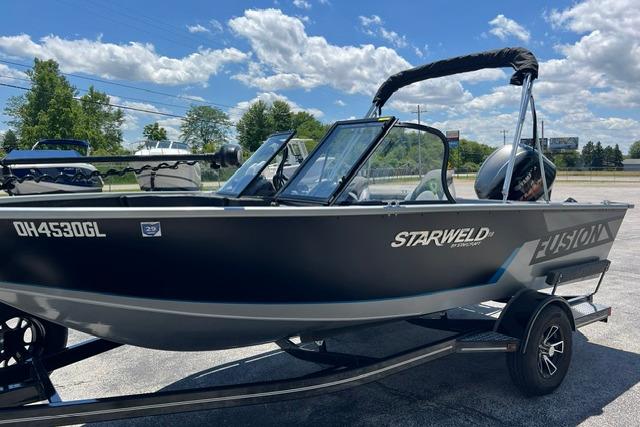 2023 Starweld Fusion 18 DC boat on trailer, parked outdoors under a blue sky.