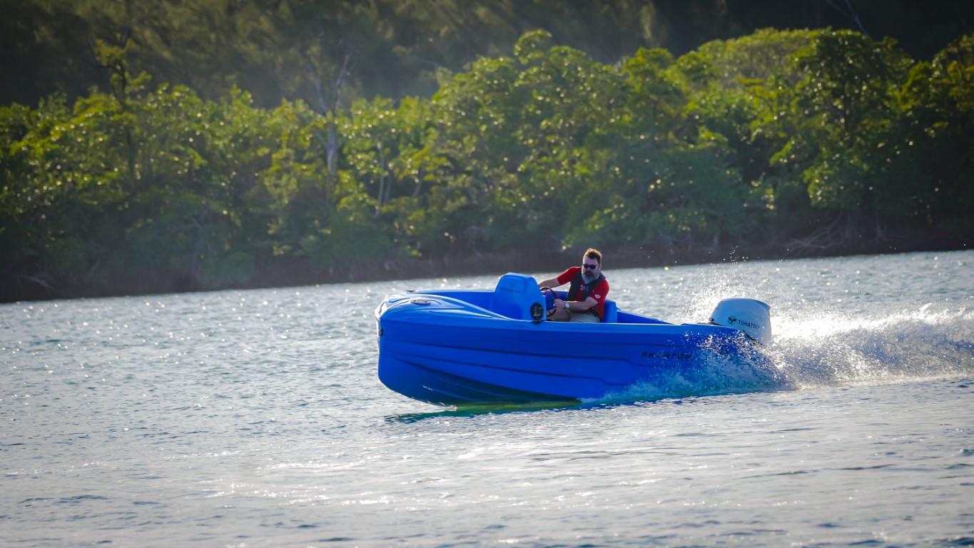 2024 Vision Marine Technologies Phantom boat cruising on a lake with lush greenery in the background.