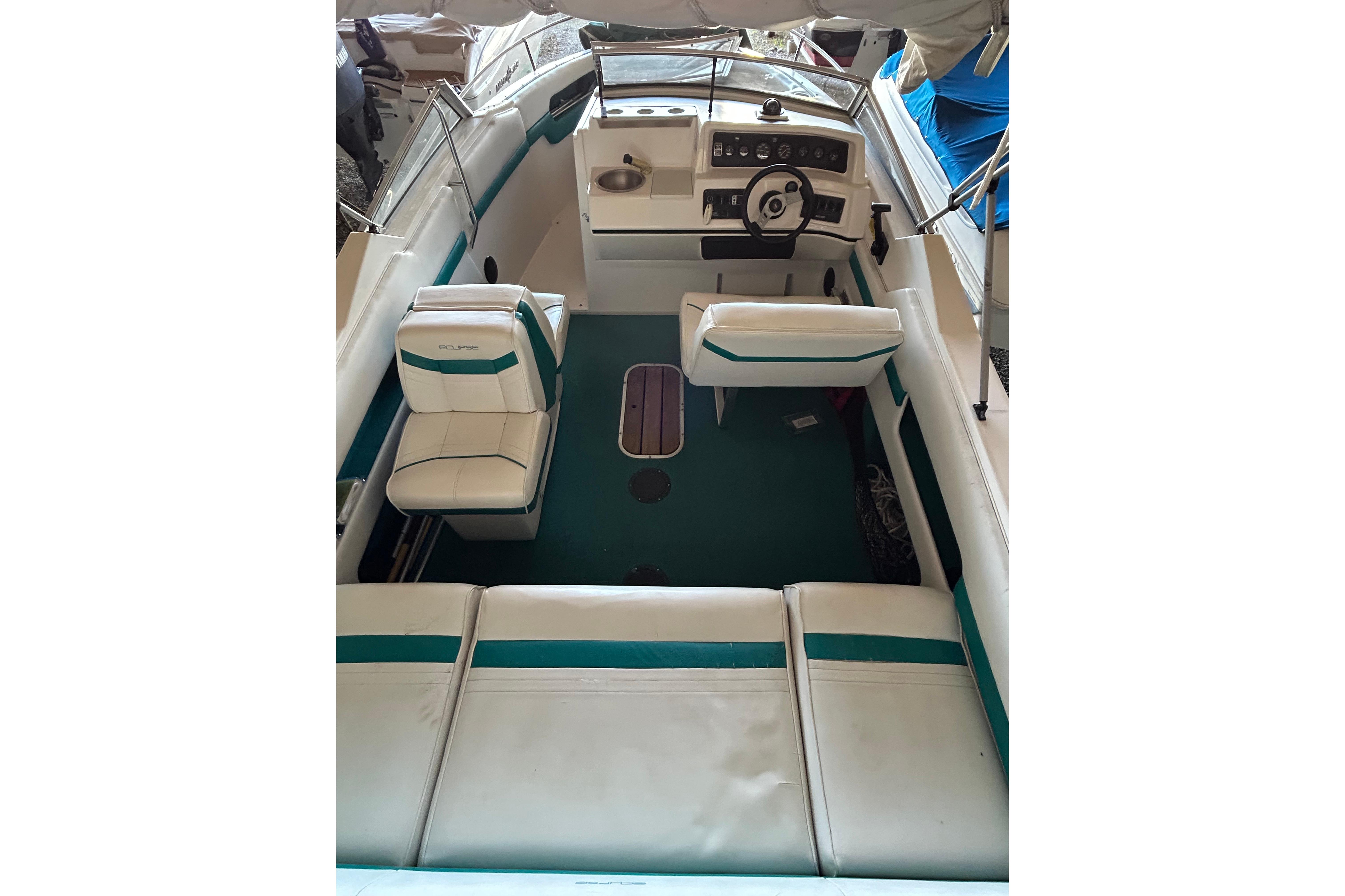 1991 Wellcraft 232 Eclipse boat interior with white and teal seating, steering wheel, and dashboard.