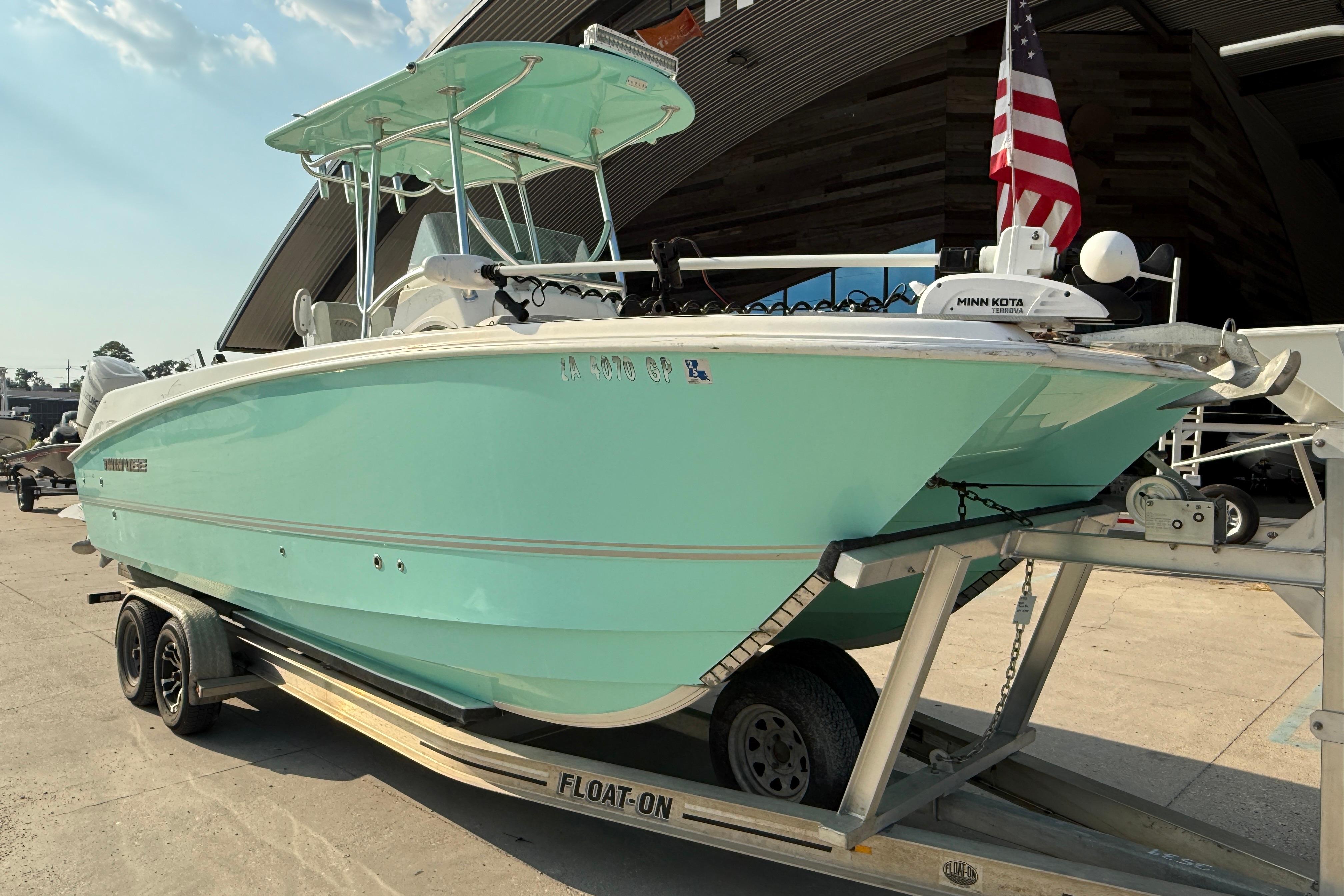 2020 Twin Vee 240 GFX CC boat on trailer, mint green hull, American flag displayed.