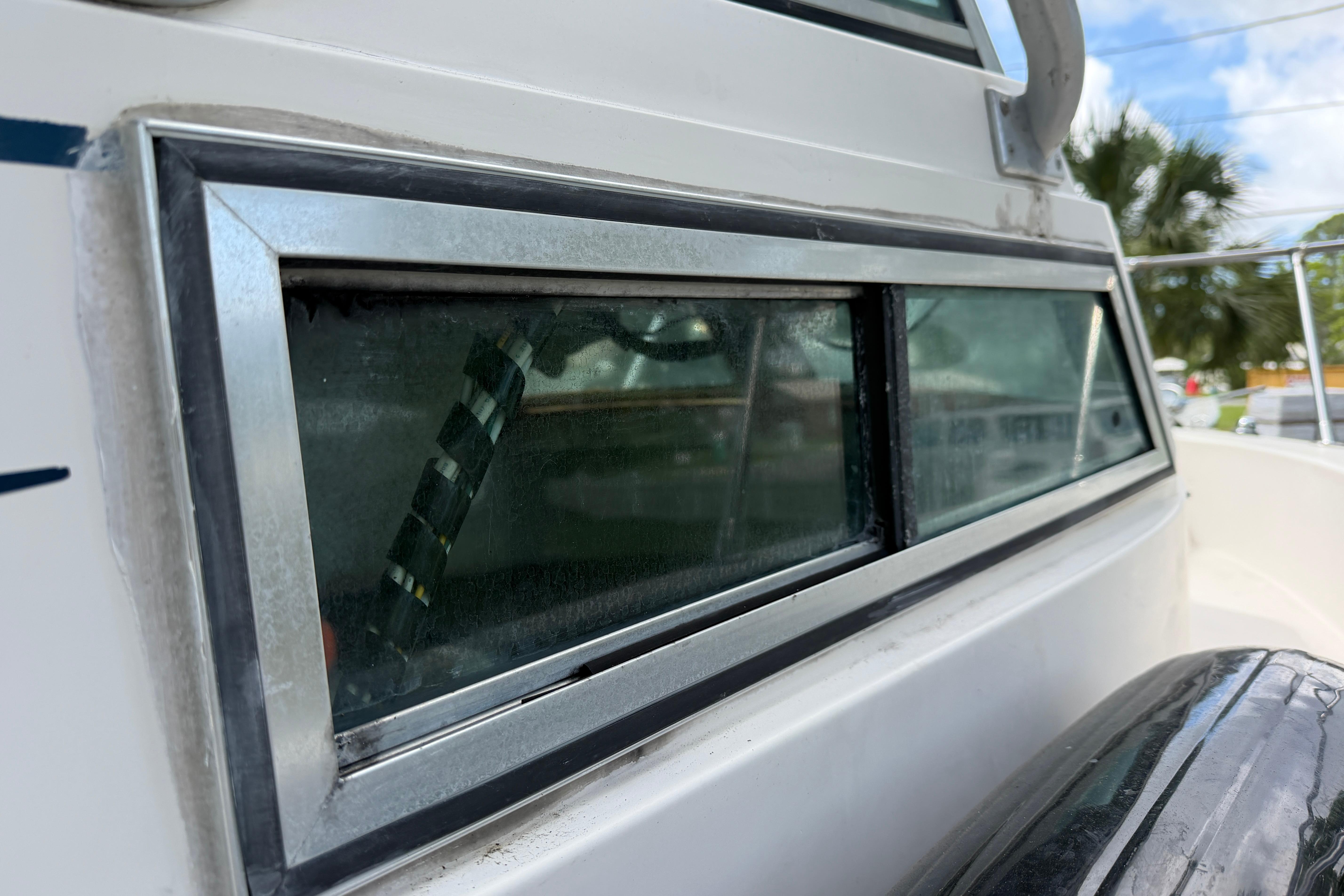 Close-up of a 1987 Grady-White Seafarer 226 boat window with metal frame.