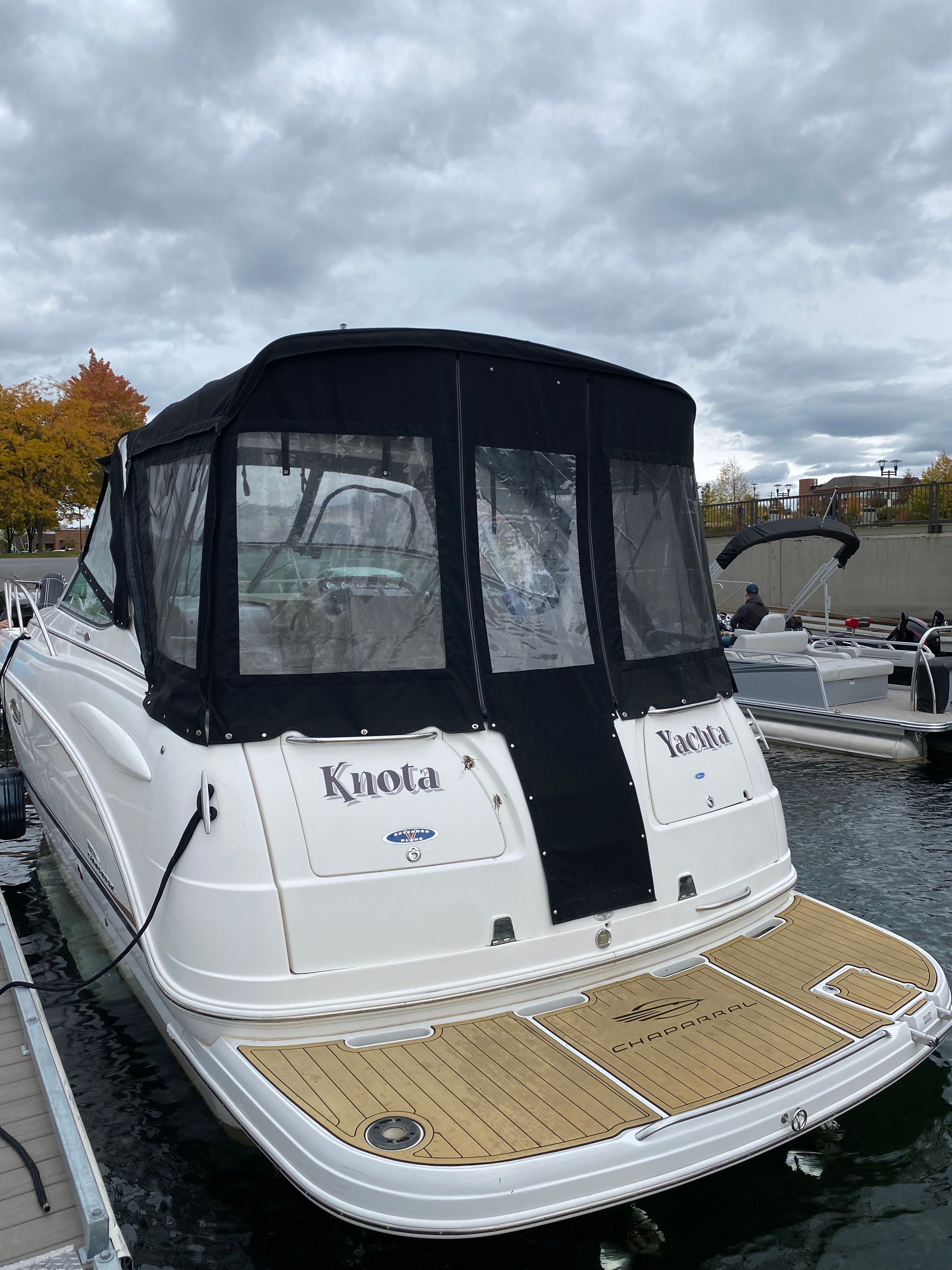 A 2004 Chaparral Signature 330 docked. It features a black canopy and a wooden platform.