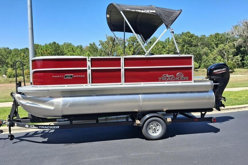 2026 Sun Tracker Party Barge 16 DLX pontoon boat on trailer, parked outdoors.