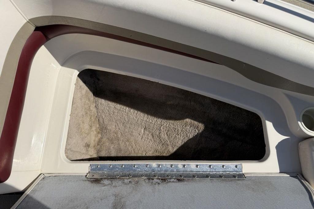 Storage compartment in a 1999 Glastron GT 225 boat, featuring carpeted interior and hinged lid.