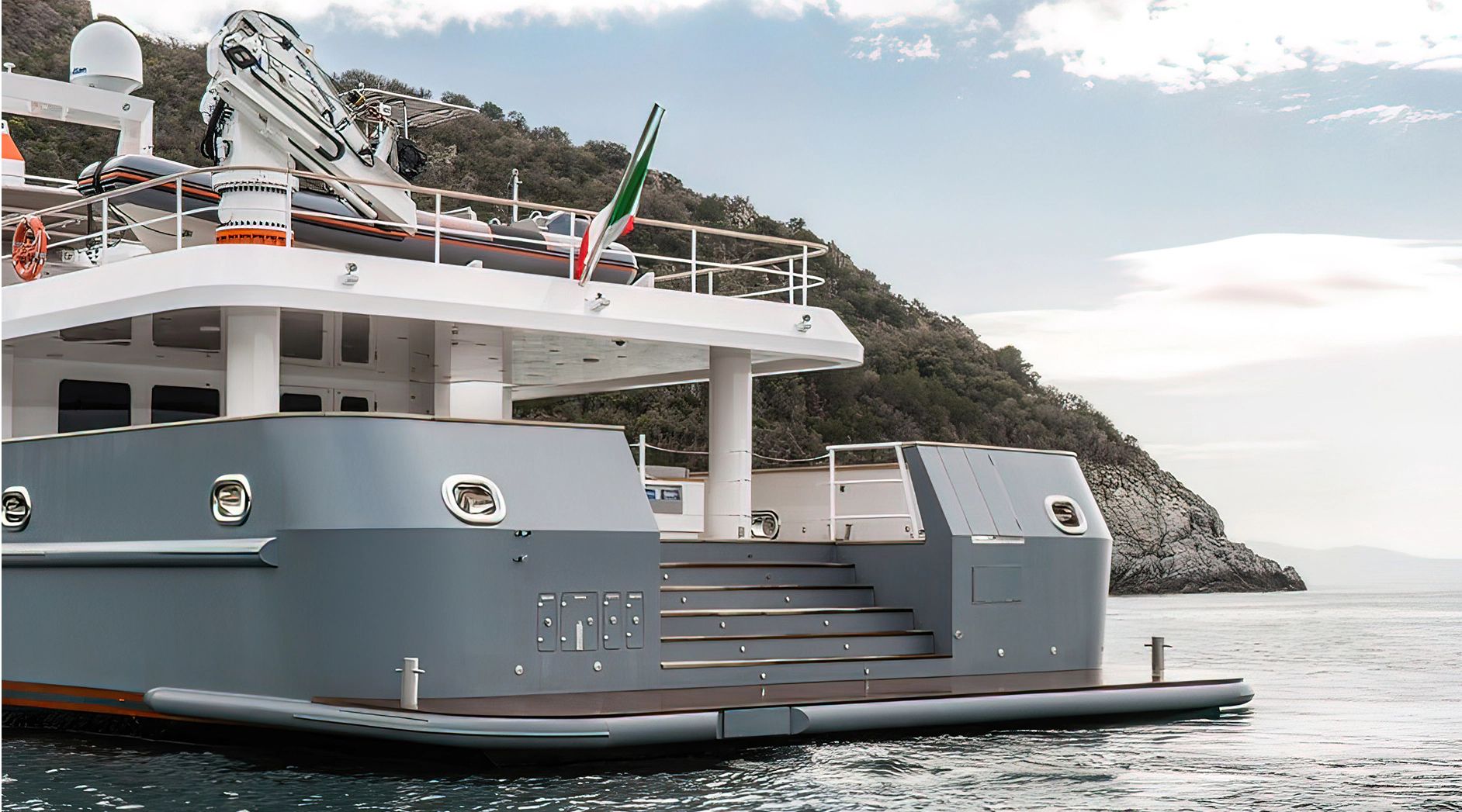 The 2028 Ocean King Explorer 130 is on the water near a rocky coastline.