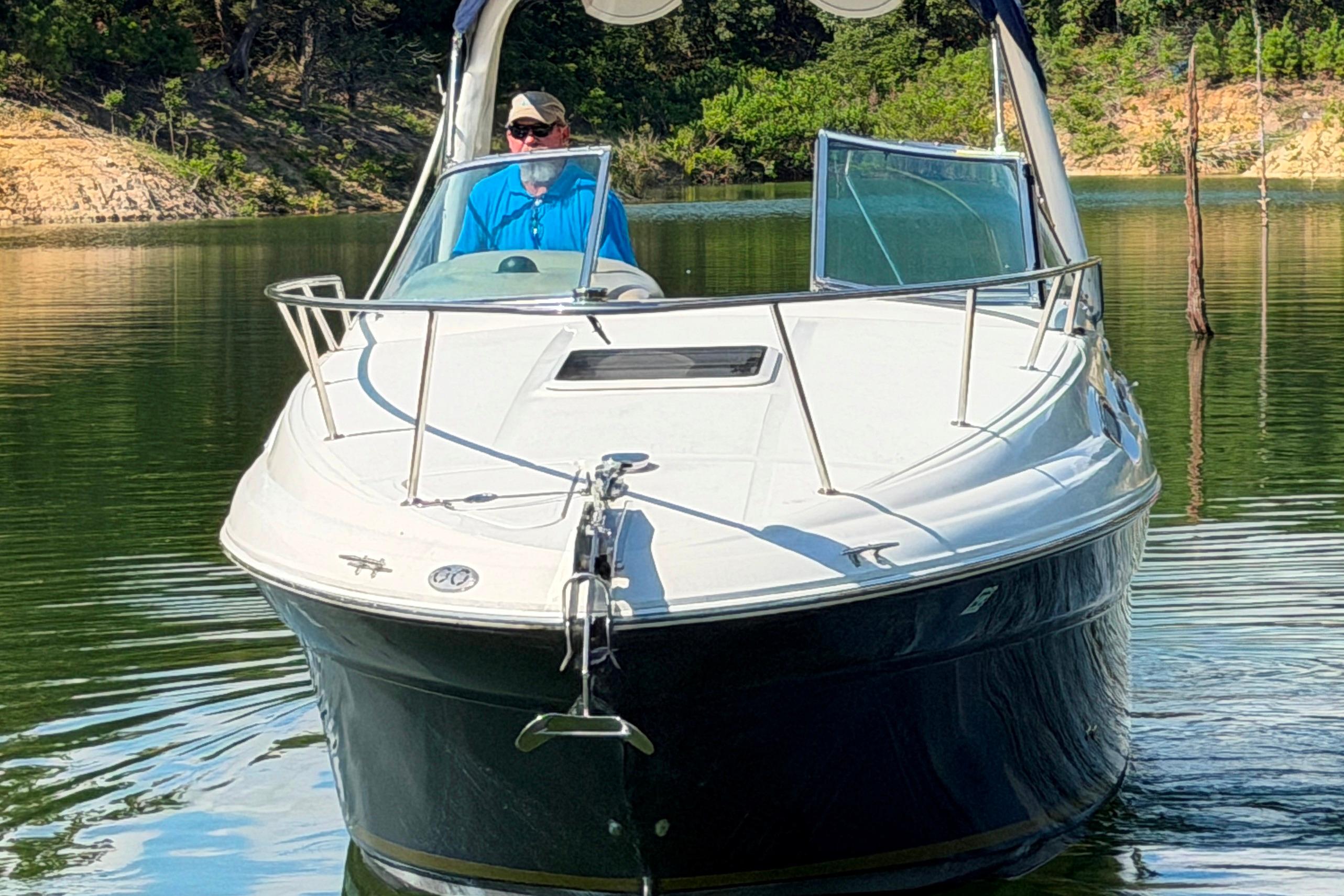 2004 Sea Ray Sundancer 260 boat on a calm lake with a person at the helm.