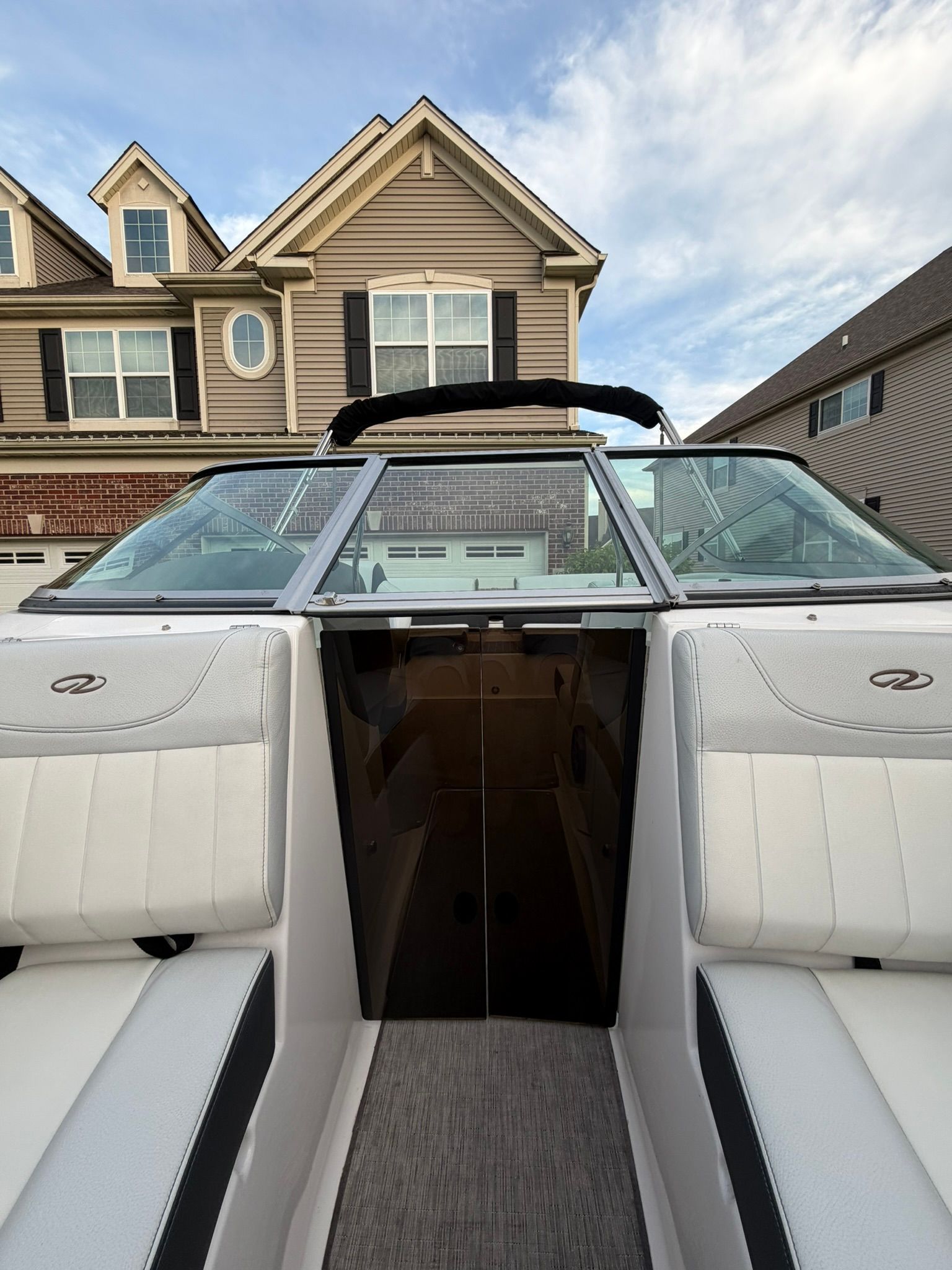 A 2015 Regal 2100 Bowrider is parked in front of a house. View of the cockpit.