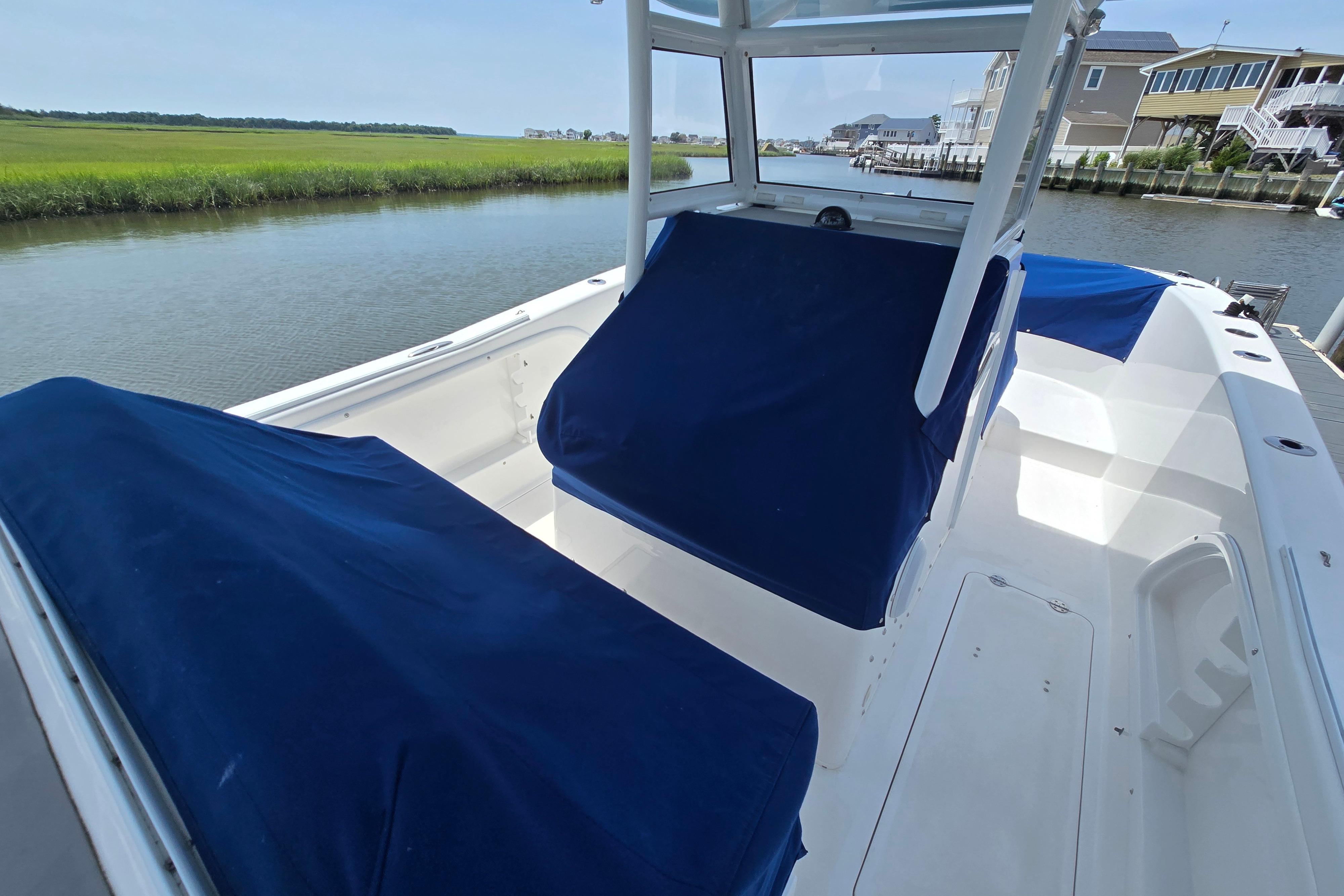 2021 Twin Vee 280 GFX CC boat with blue covers docked by a serene waterway.