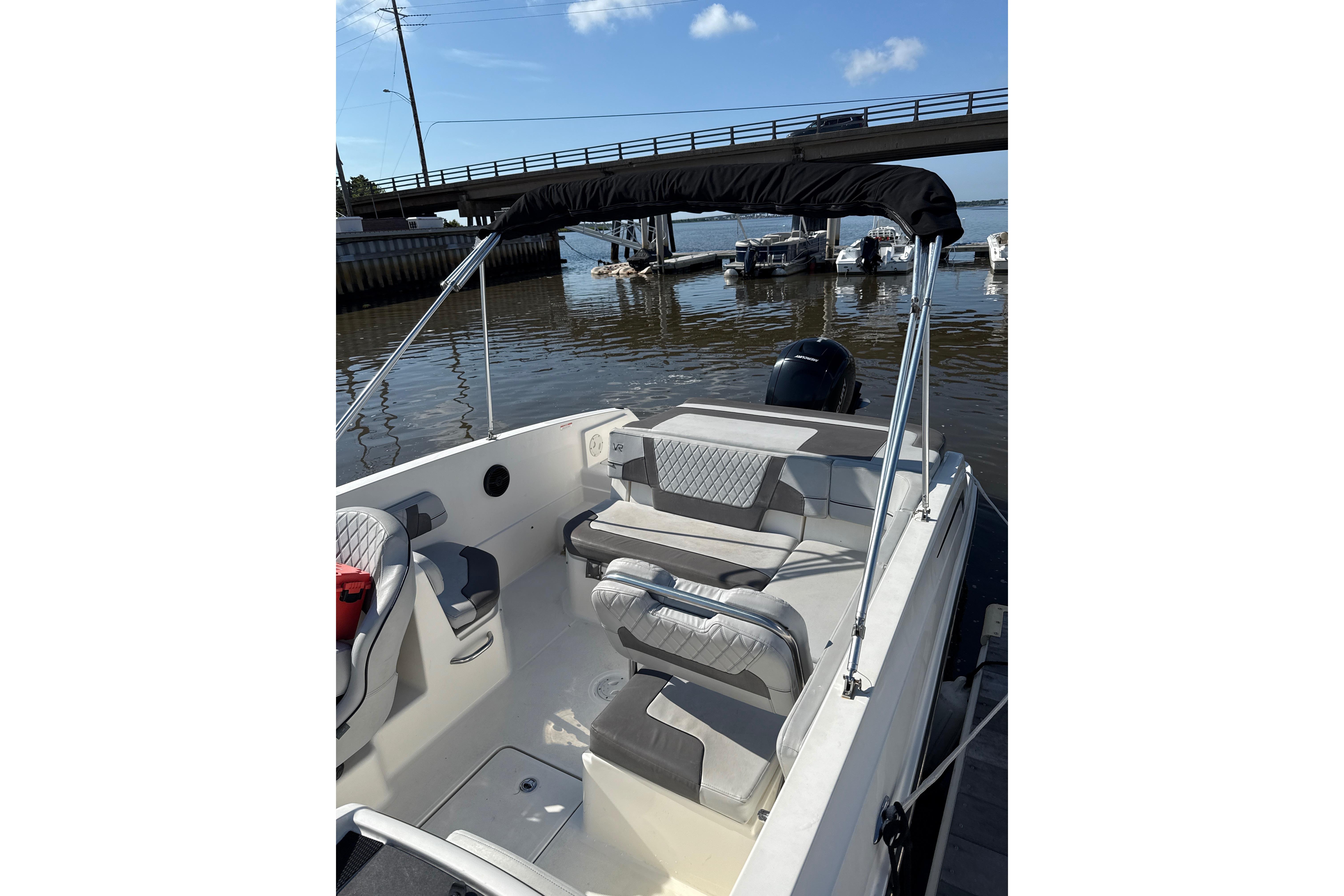 2023 Bayliner VR6 Bowrider OB with seating, docked near a bridge on a sunny day.